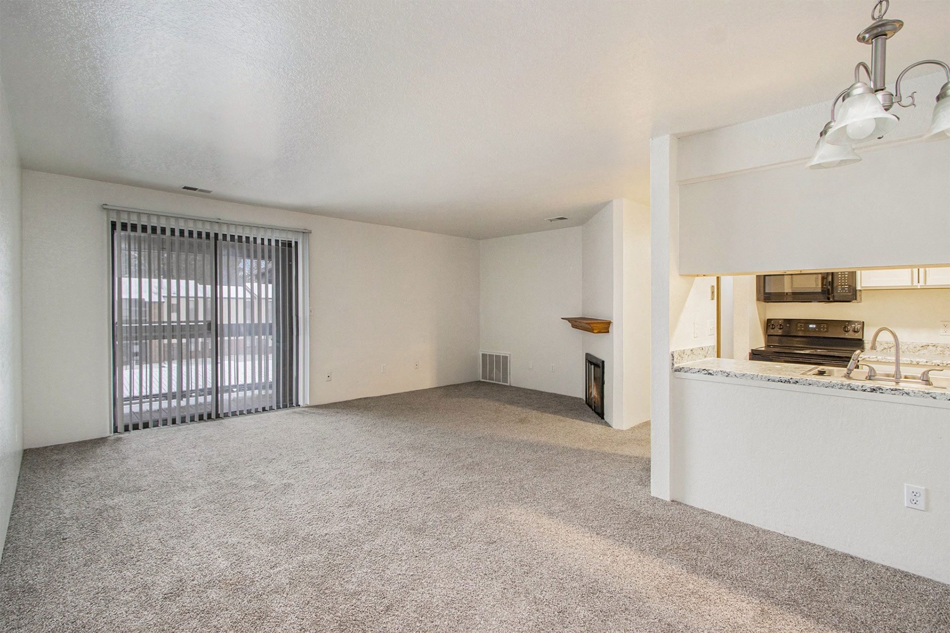 an empty living room with a window and a kitchen