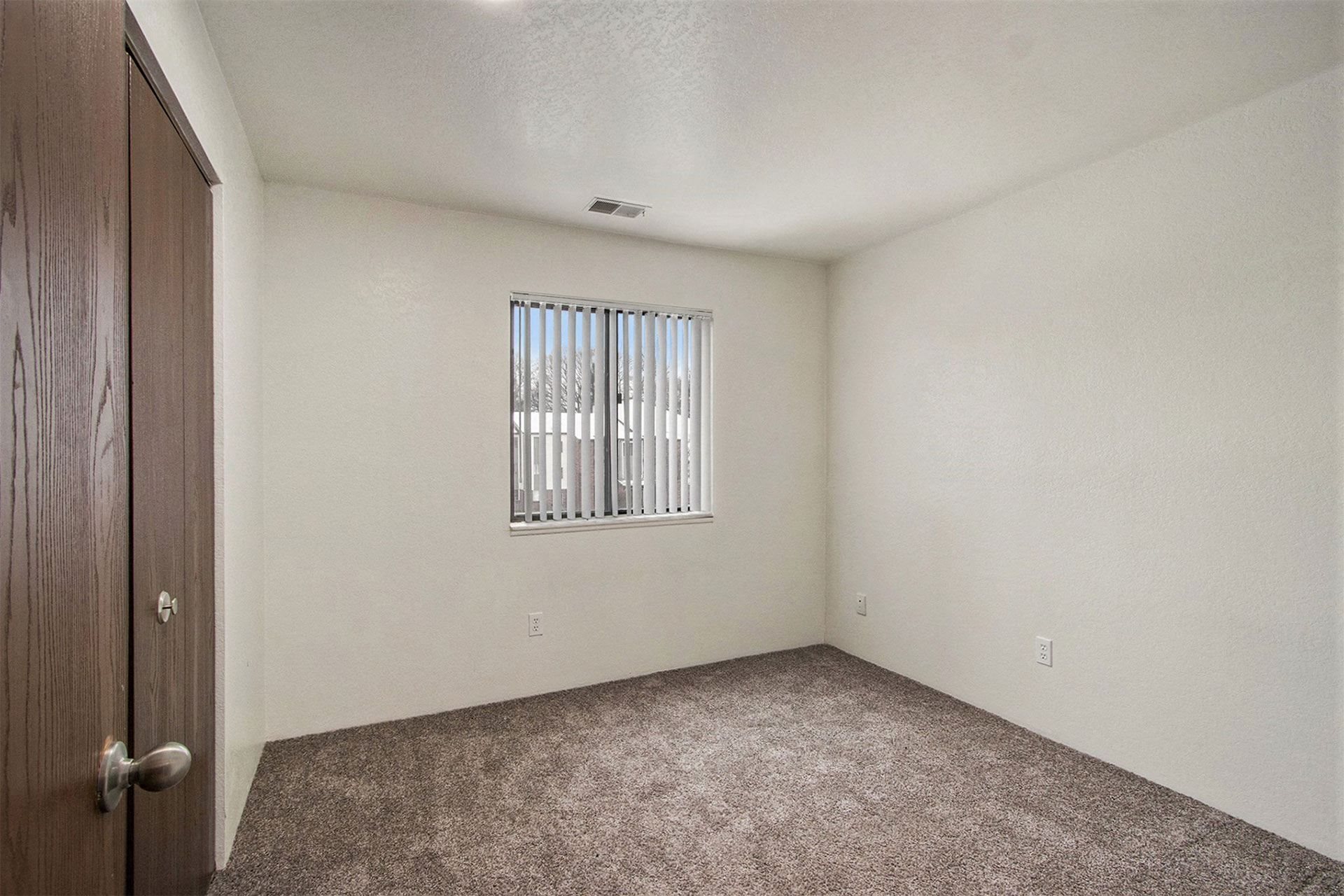 the living room of an empty home with a window and carpet