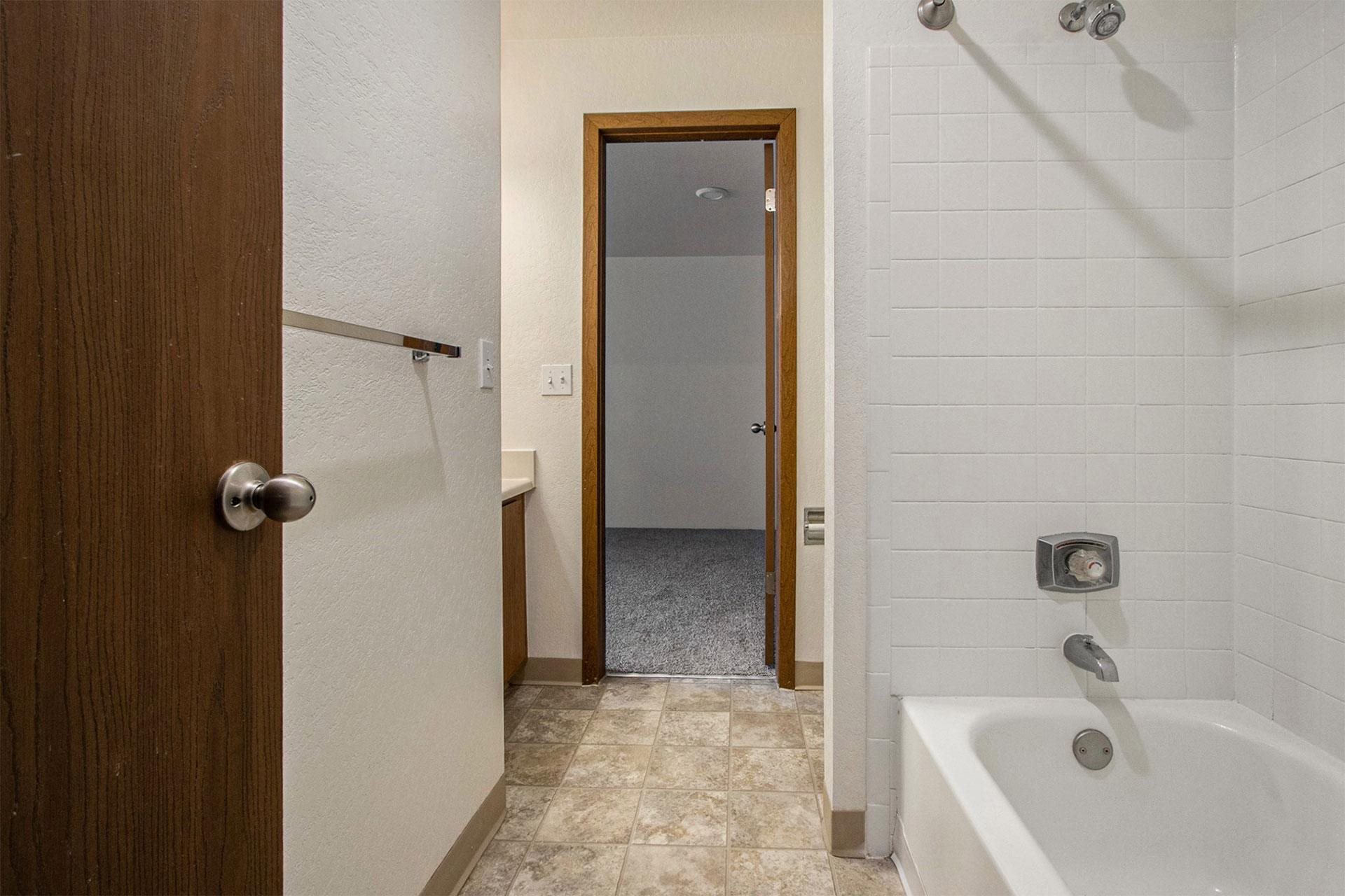 a bathroom with a tub and a shower and a door to a closet