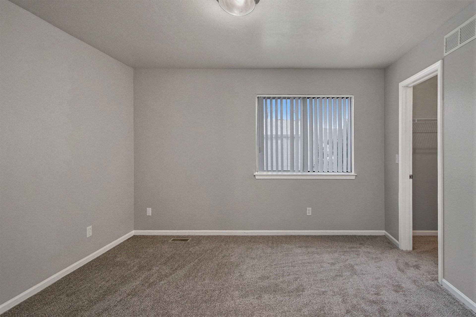 an empty living room with a window and carpet
