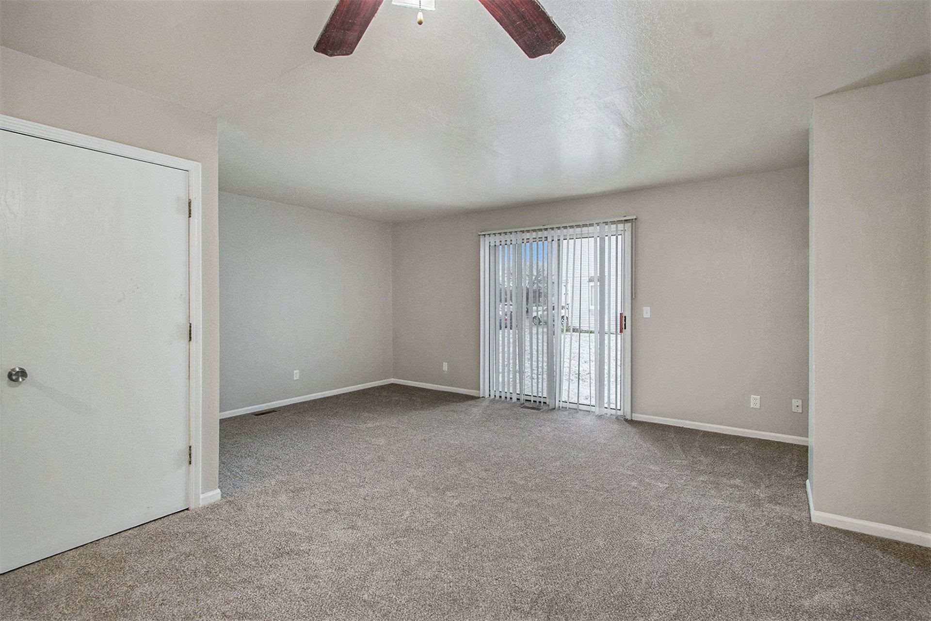 an empty living room with a sliding glass door to a patio