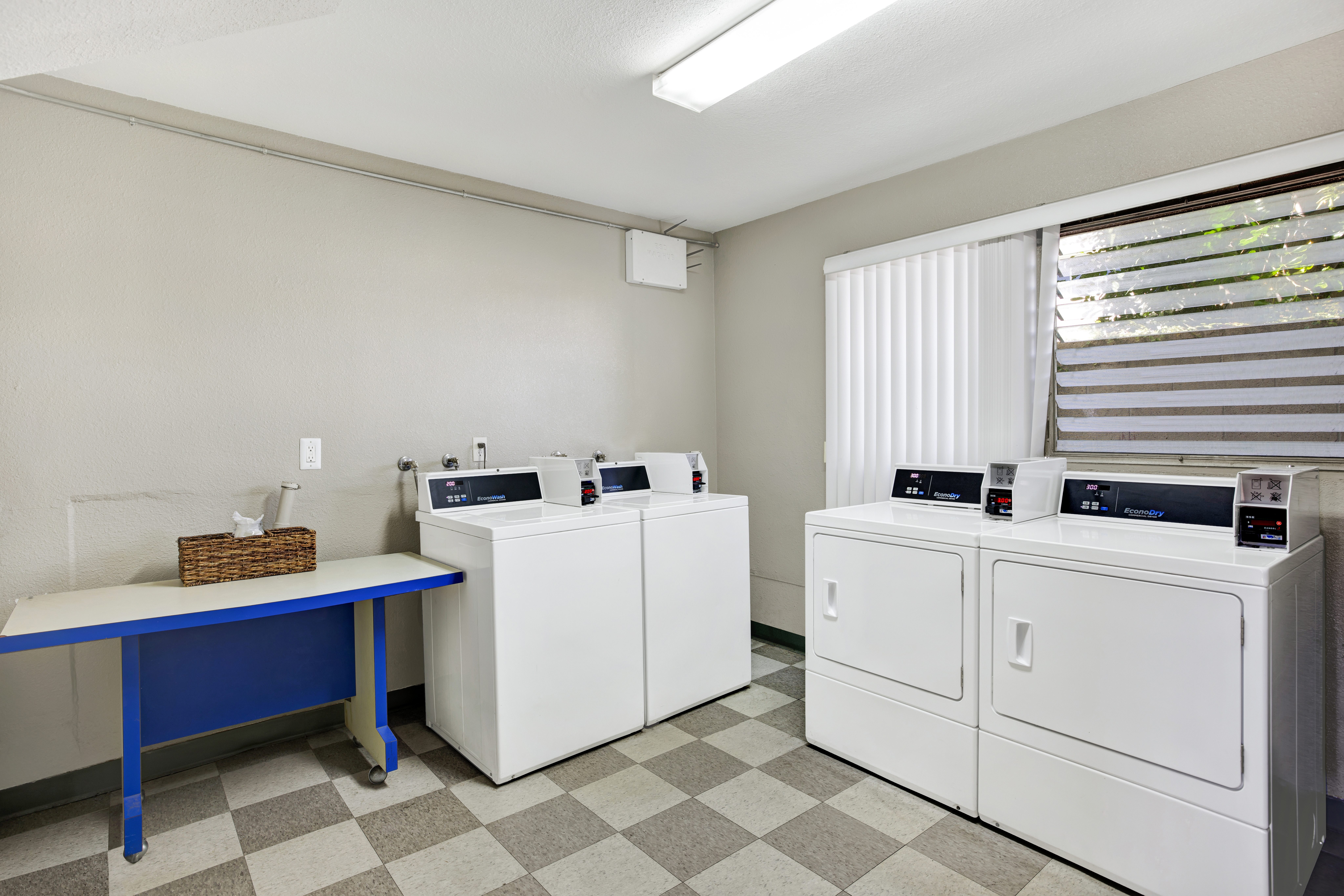 A laundry room with a blue table and white washers and dryers.