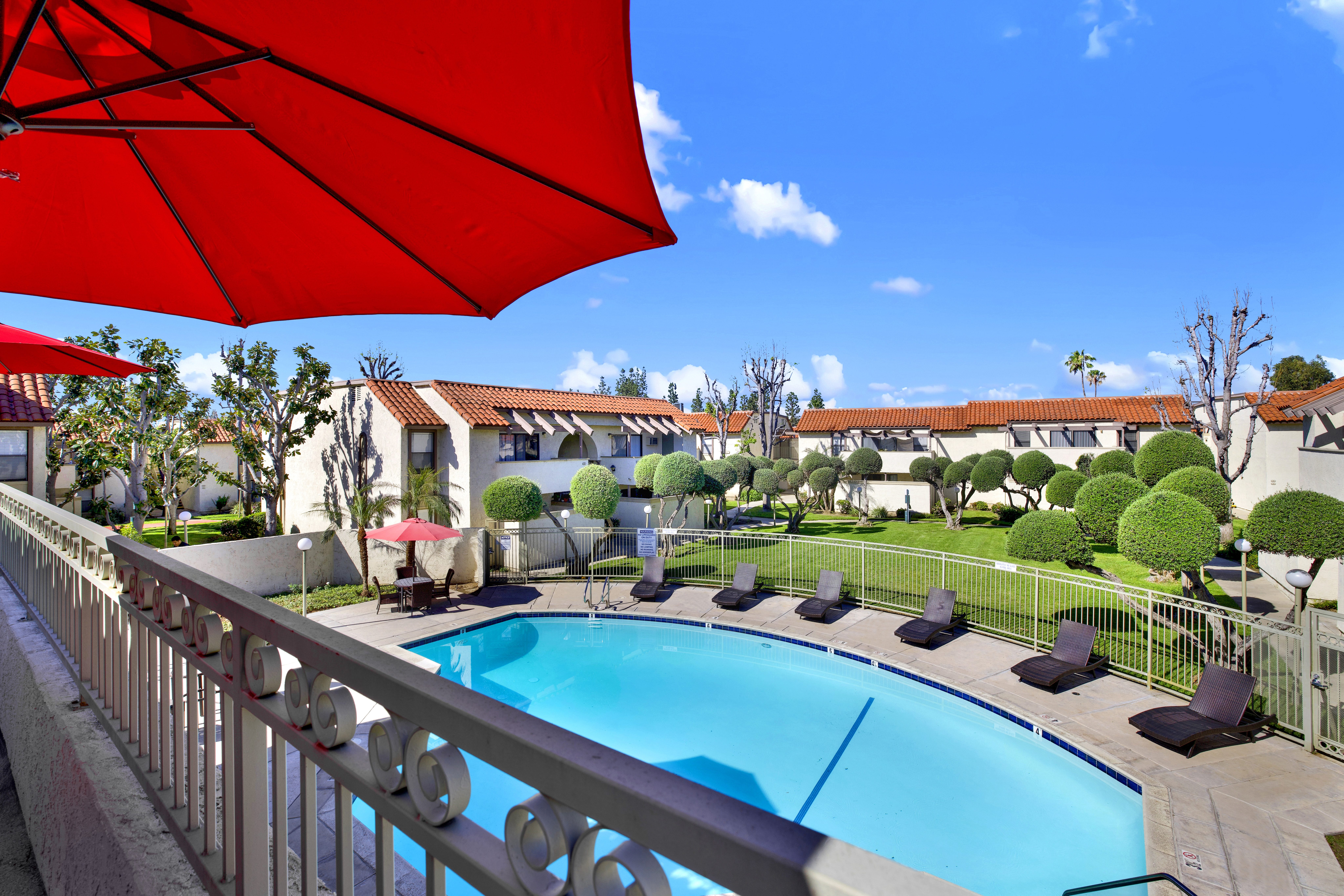 A red umbrella is over a pool.