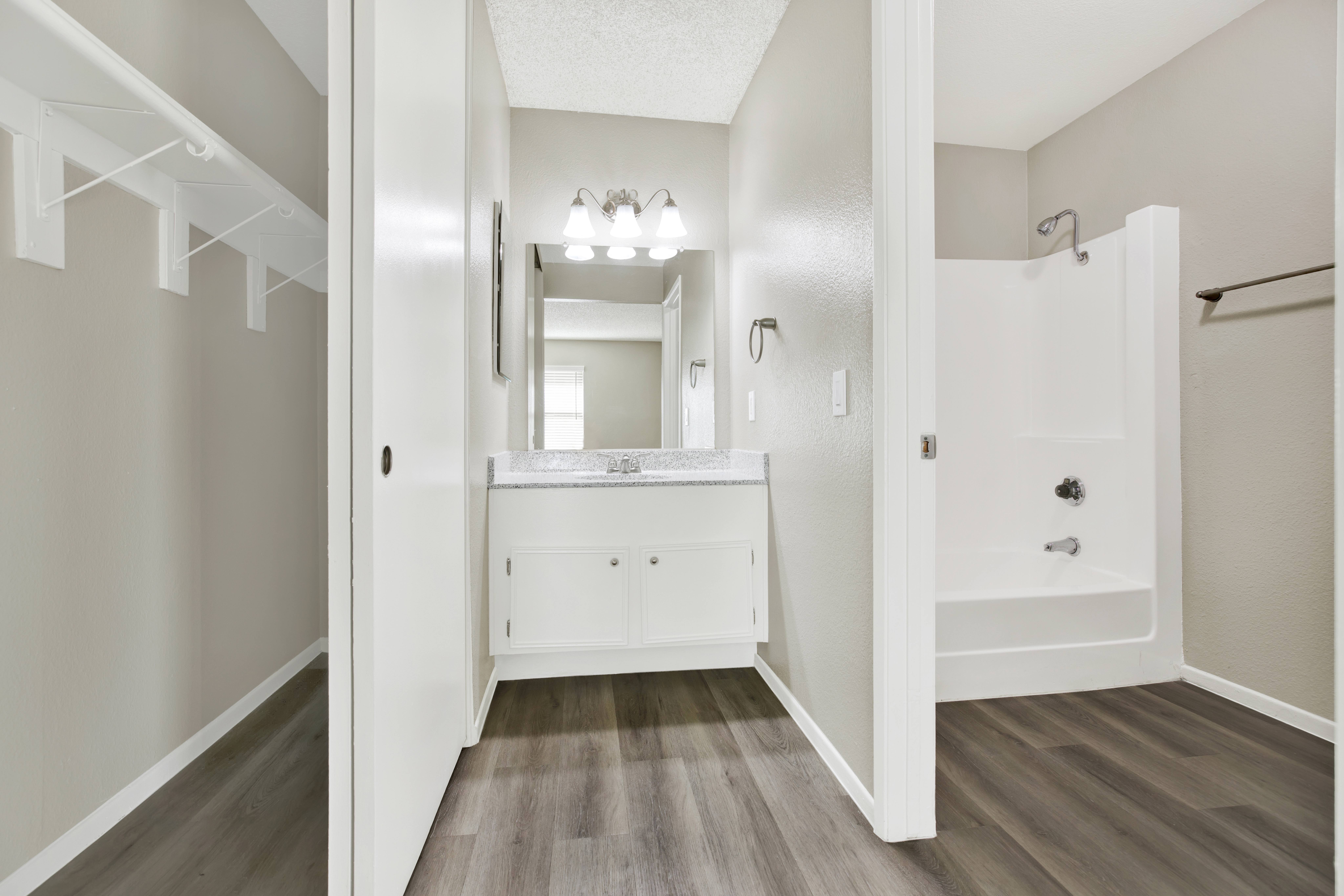 A white bathroom with a vanity and a walk-in shower.