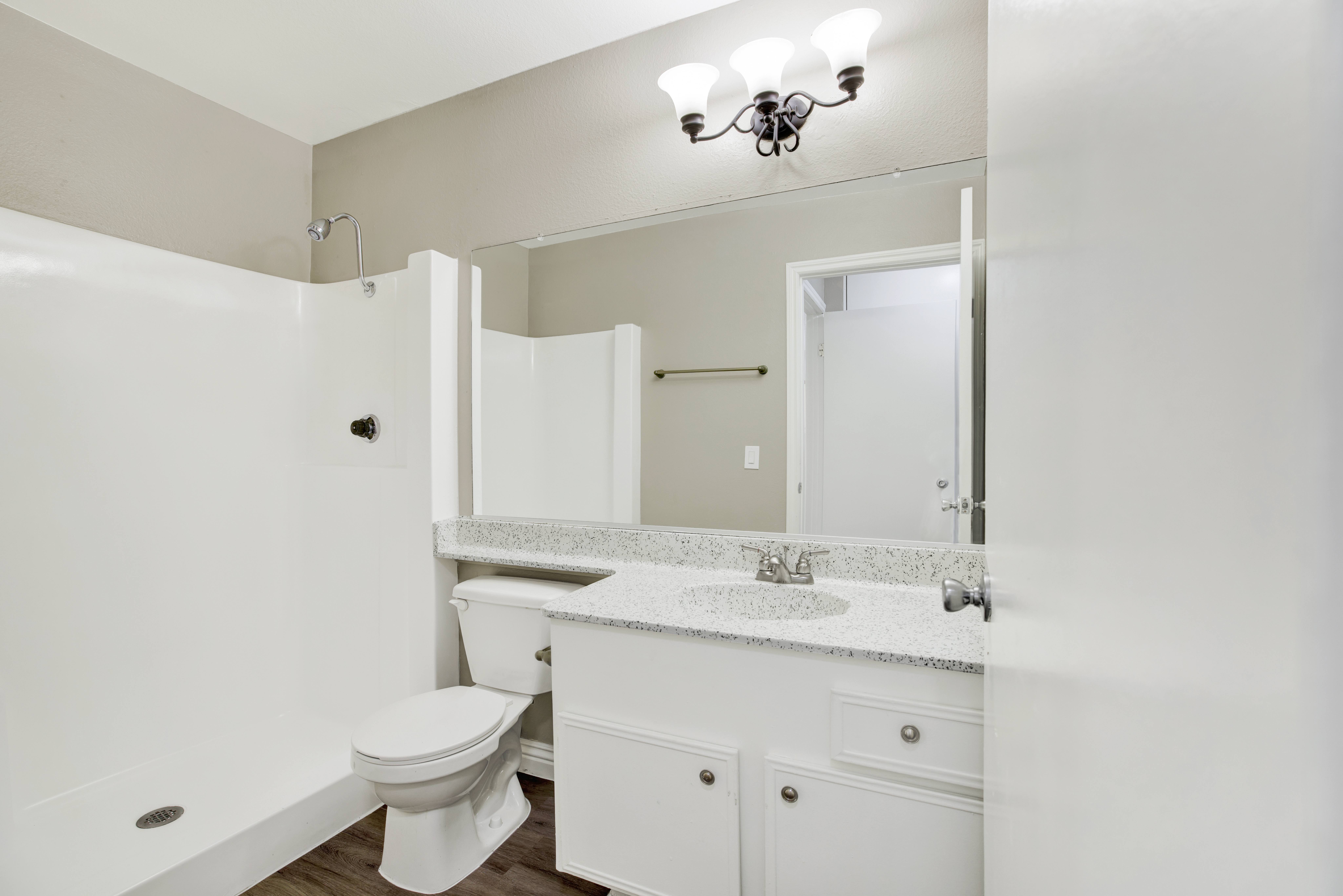 A white bathroom with a toilet, sink, and mirror.