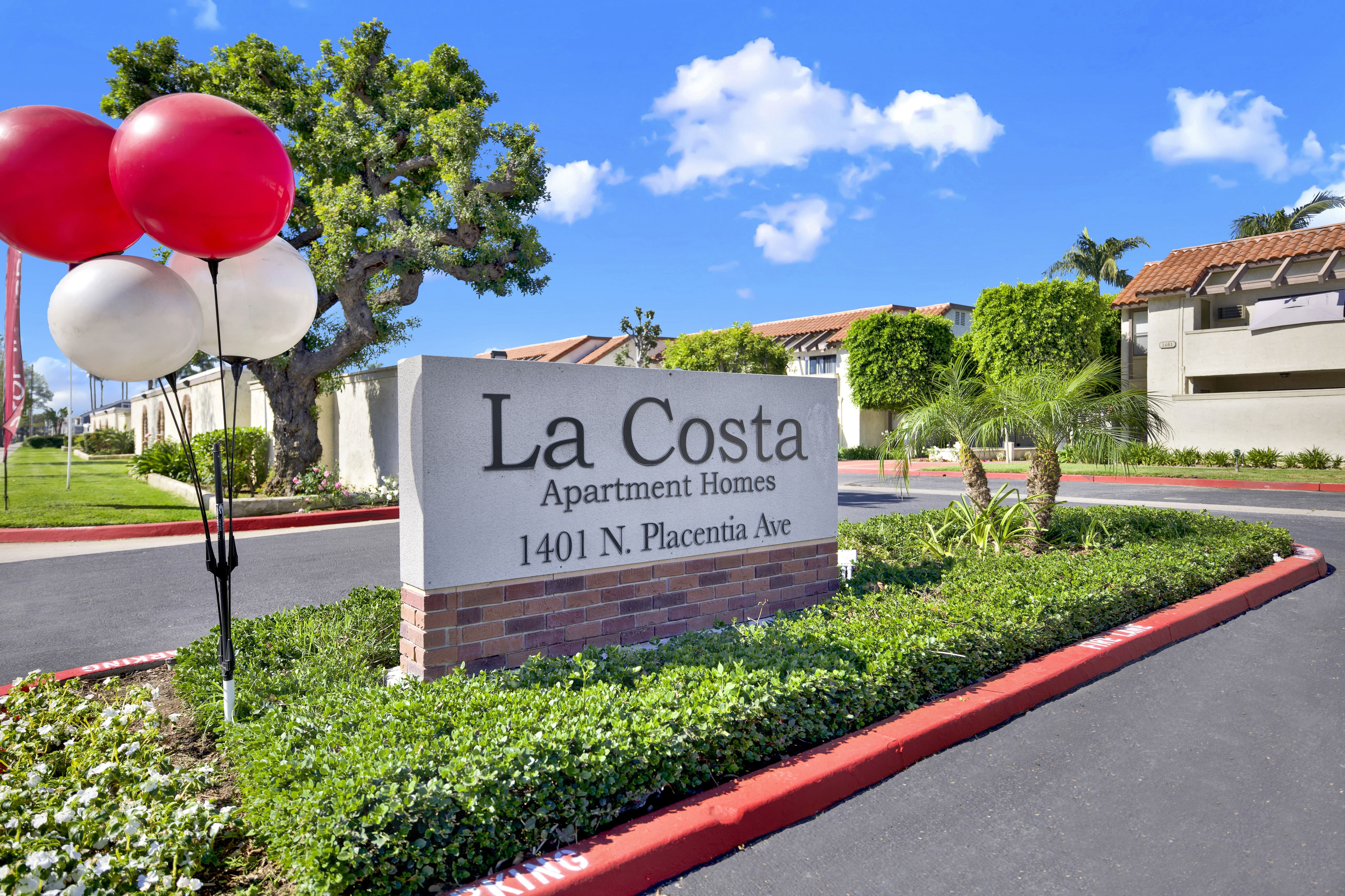 A sign for La Costa Apartment Homes stands in front of a building.