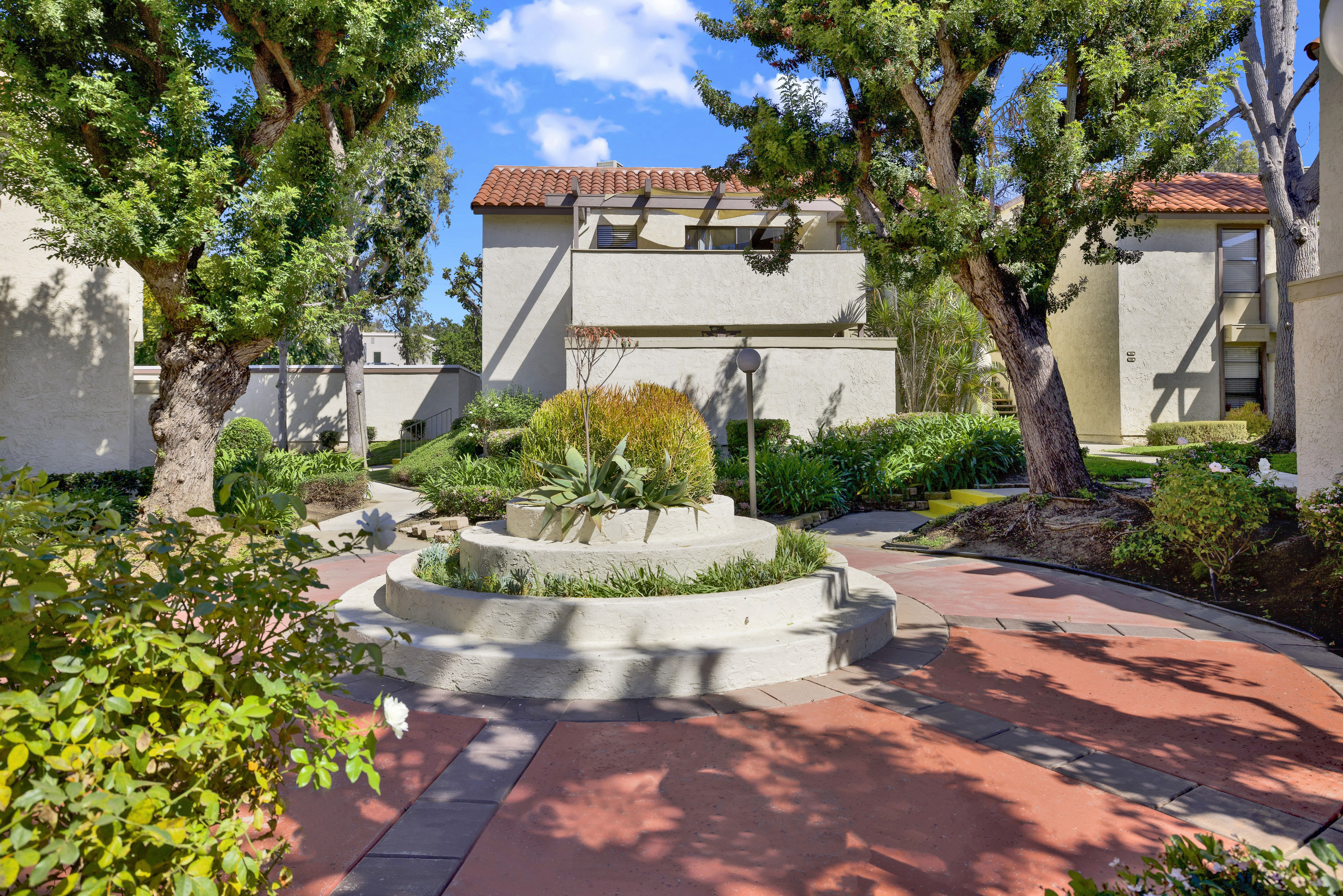 A courtyard with a fountain surrounded by trees and buildings.