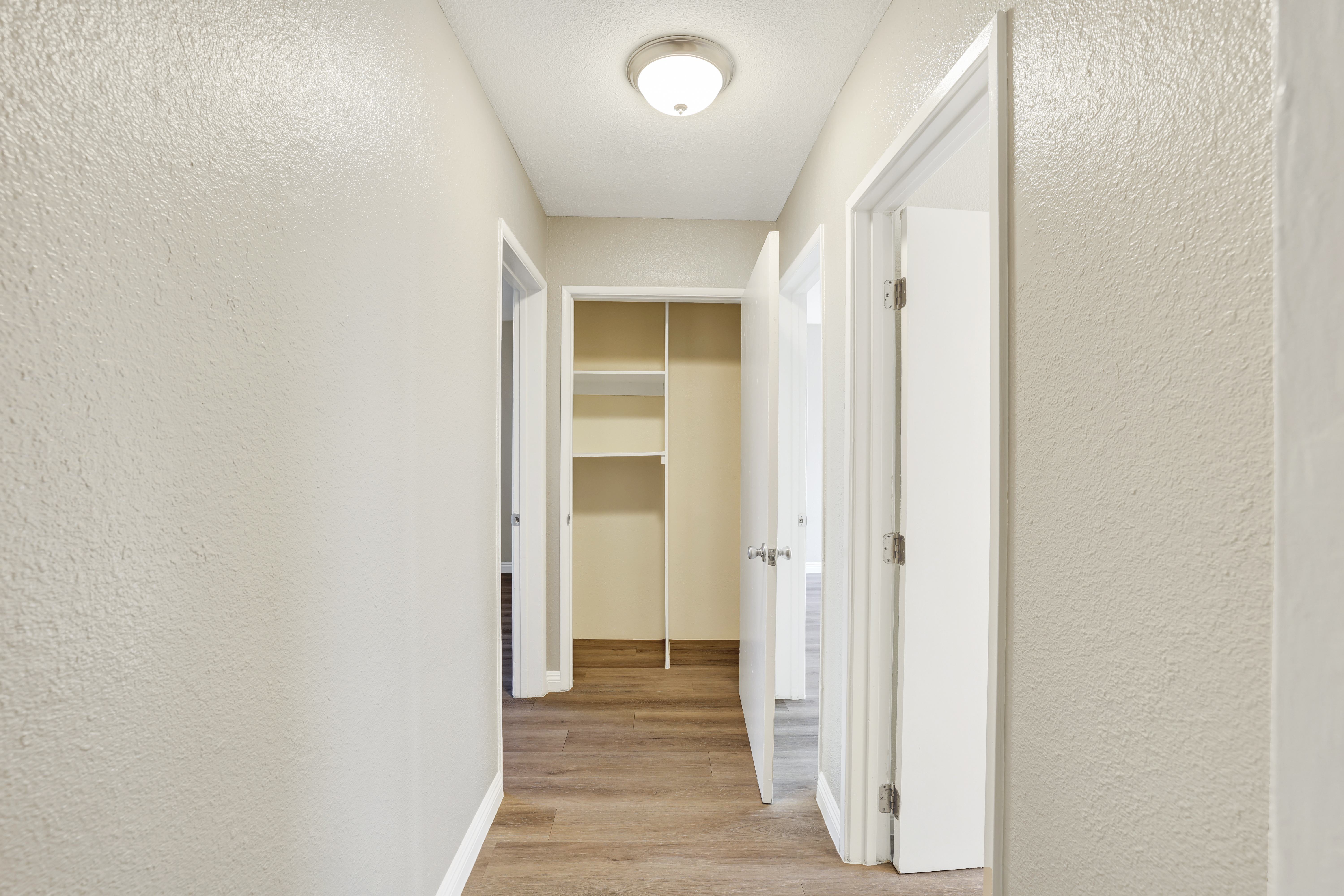 A long hallway with white walls and a light on the ceiling.