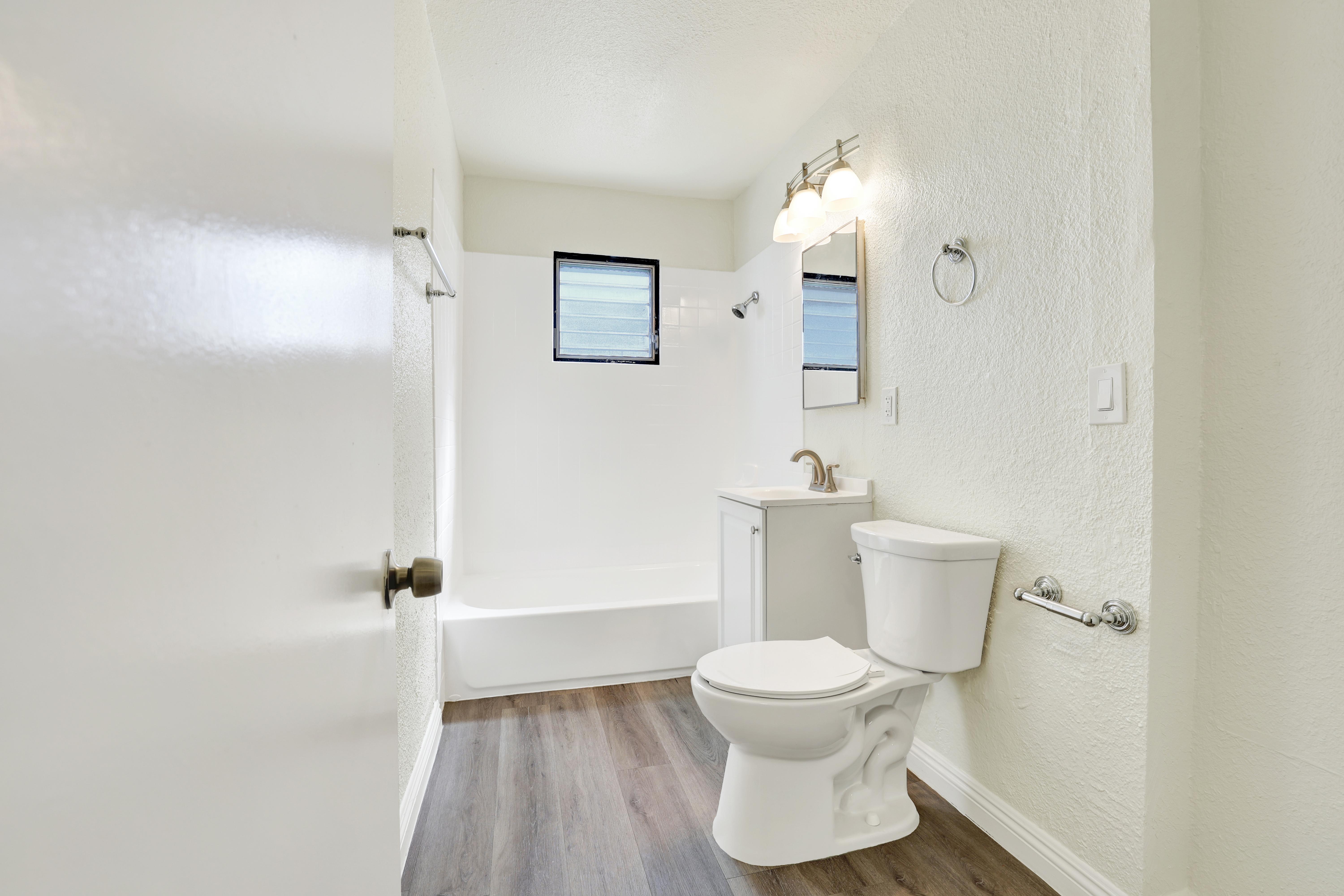 A white toilet in a small bathroom with a mirror above it.