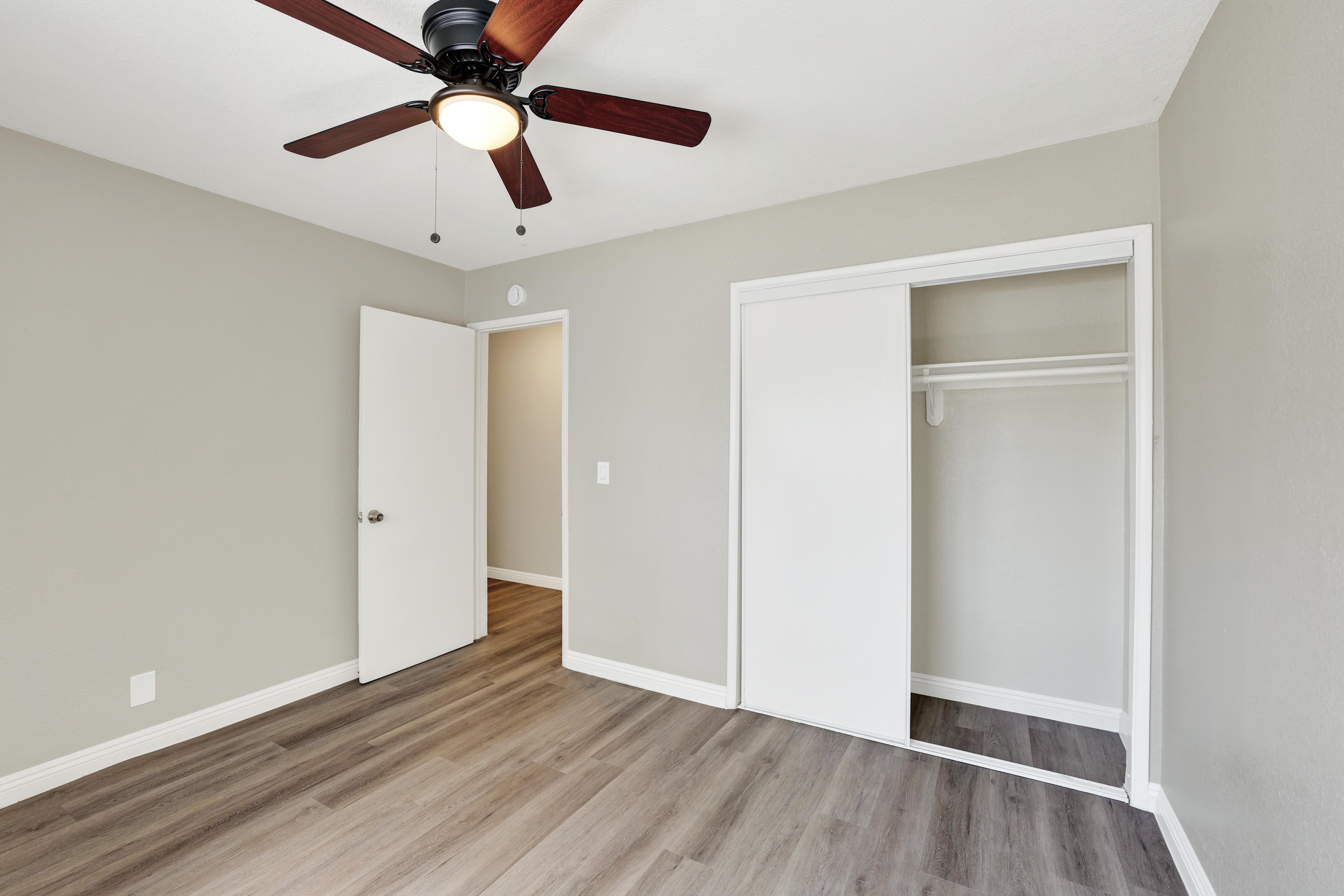 A room with a ceiling fan and a doorway leading to another room.
