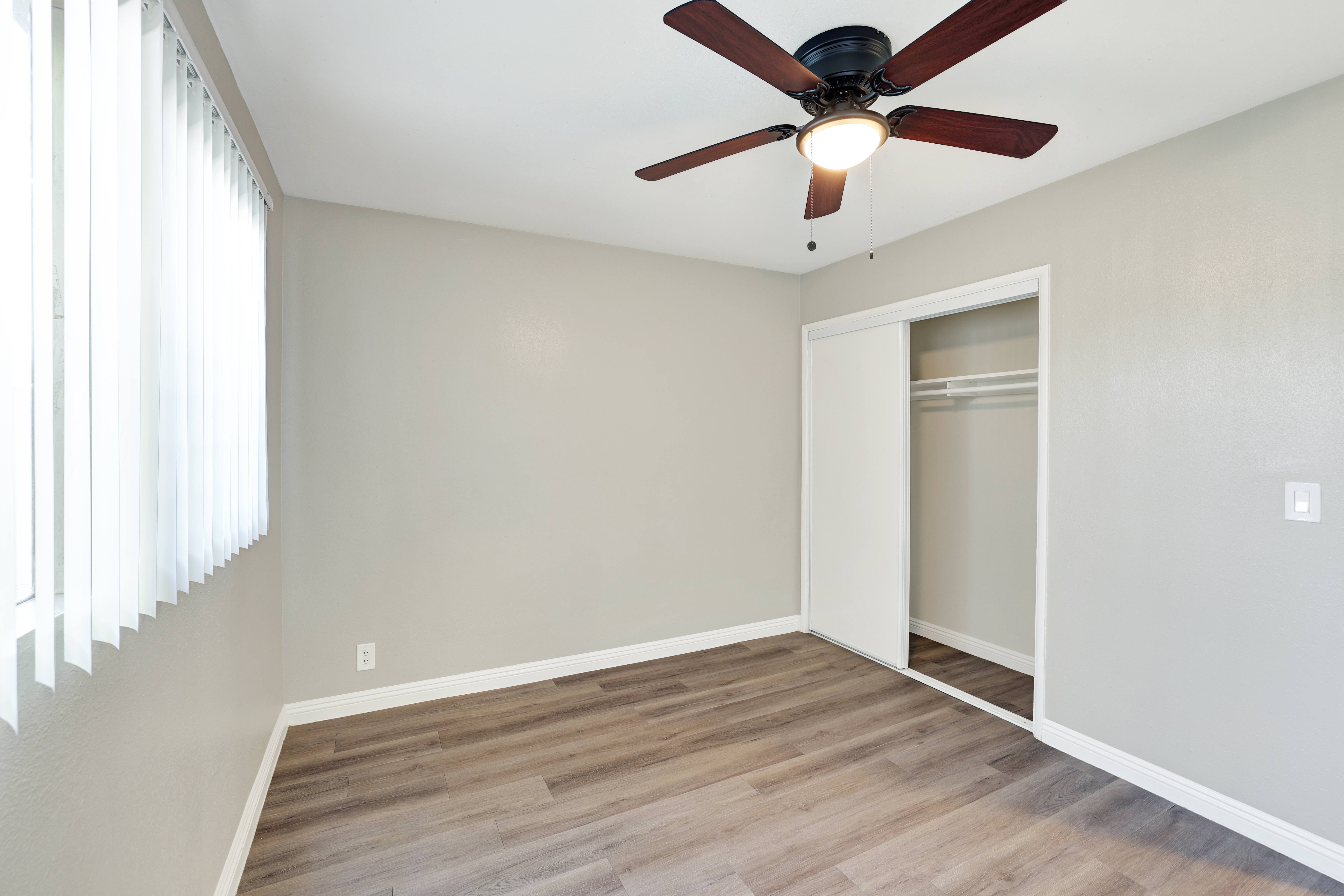 A room with a ceiling fan and wooden flooring.