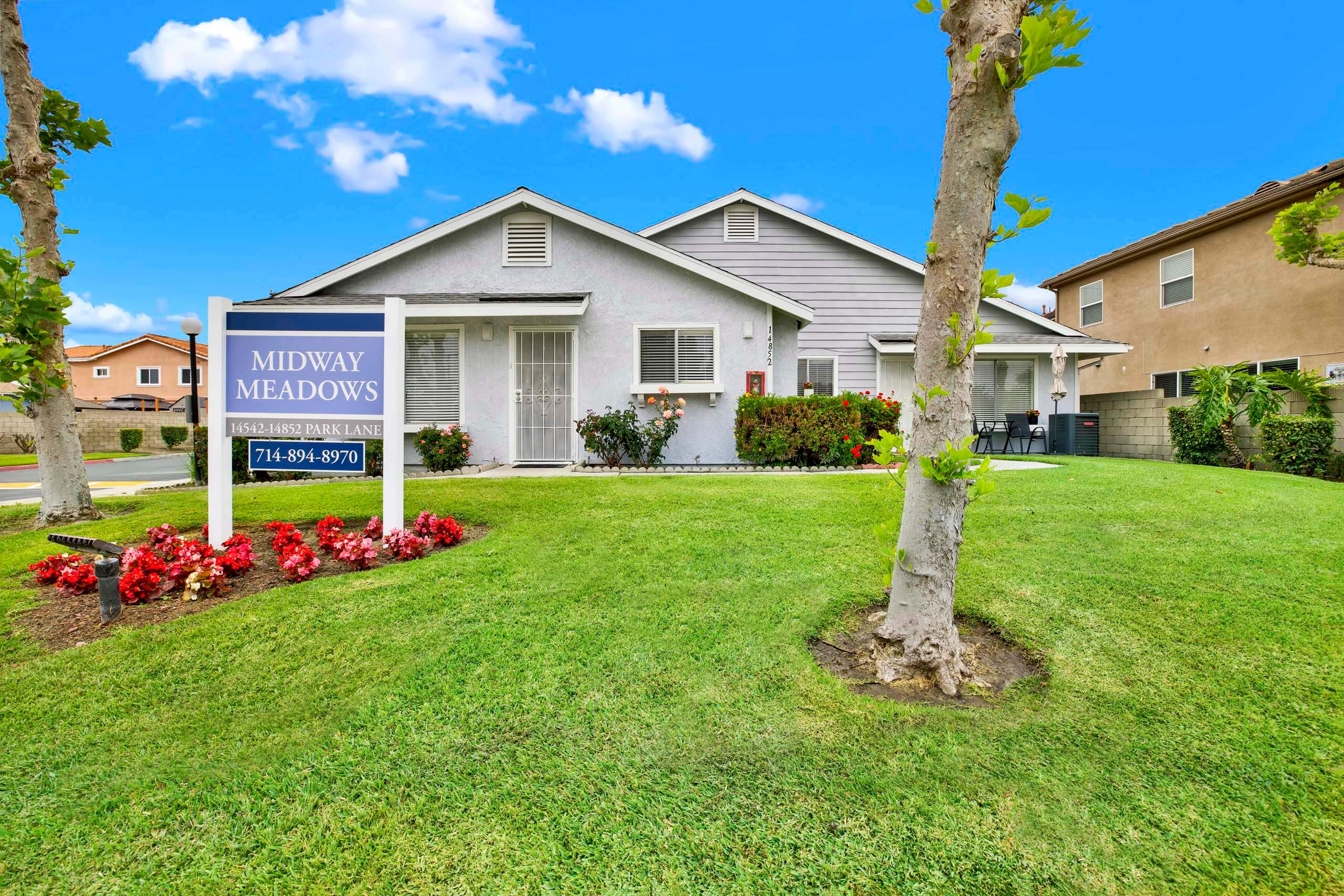 A sign for Midway Meadows is in front of a house.