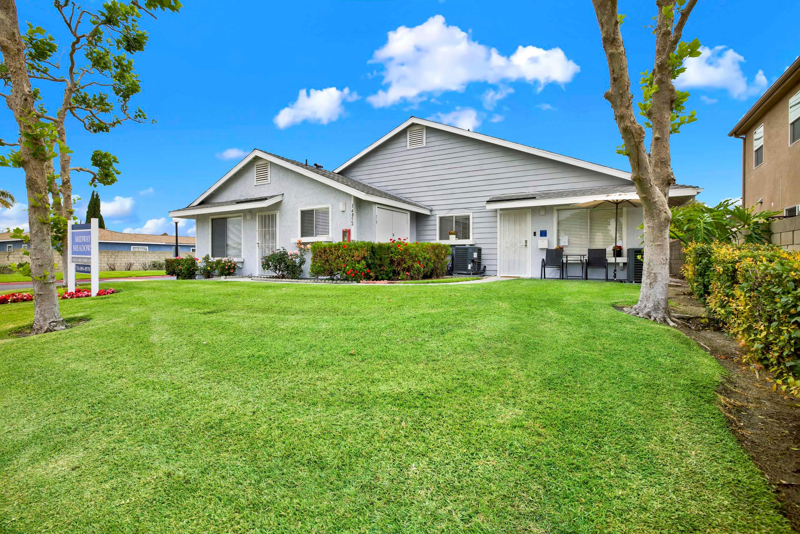 A house with a well-maintained lawn and trees in front.