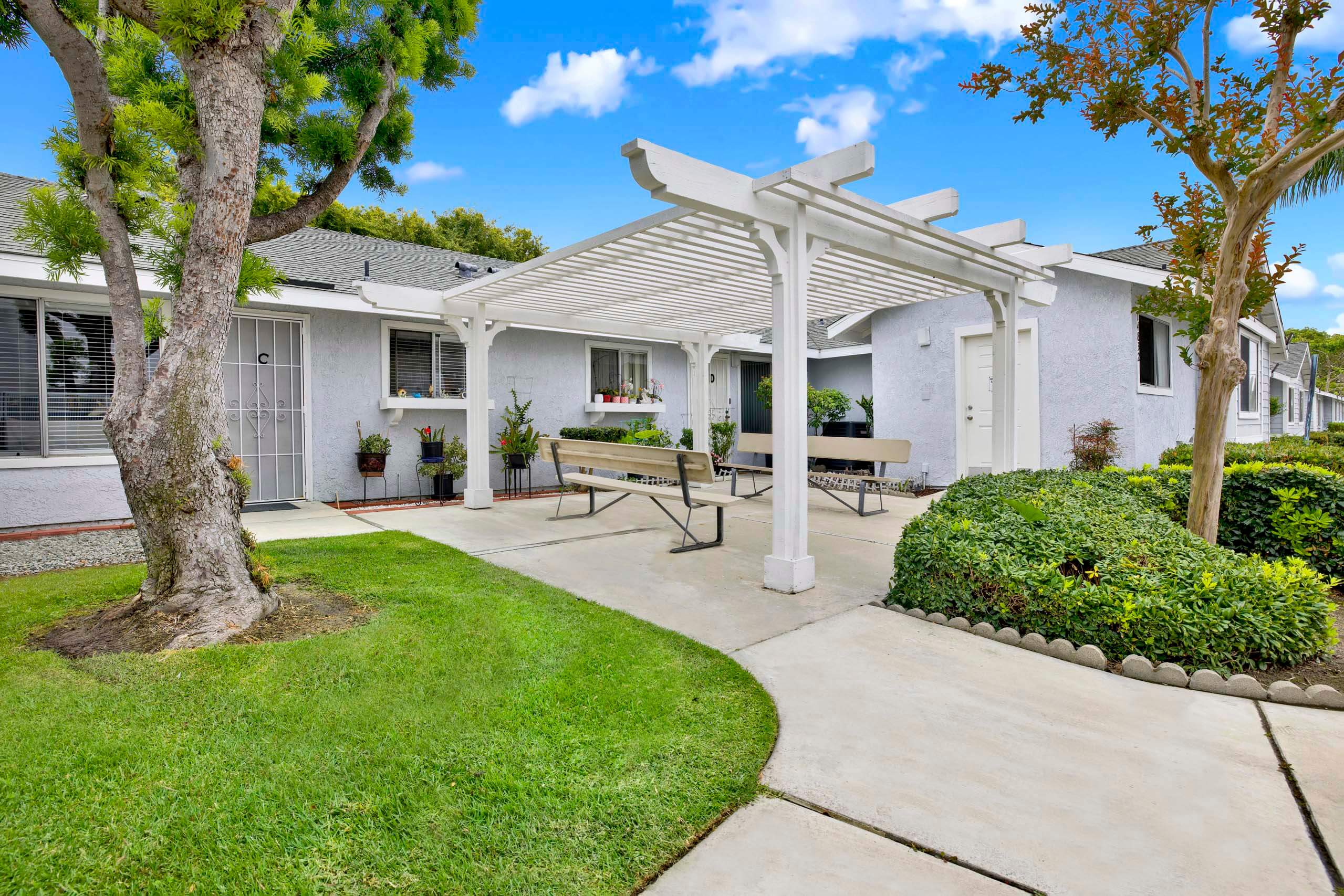 A white building with a white pergola and a white bench.