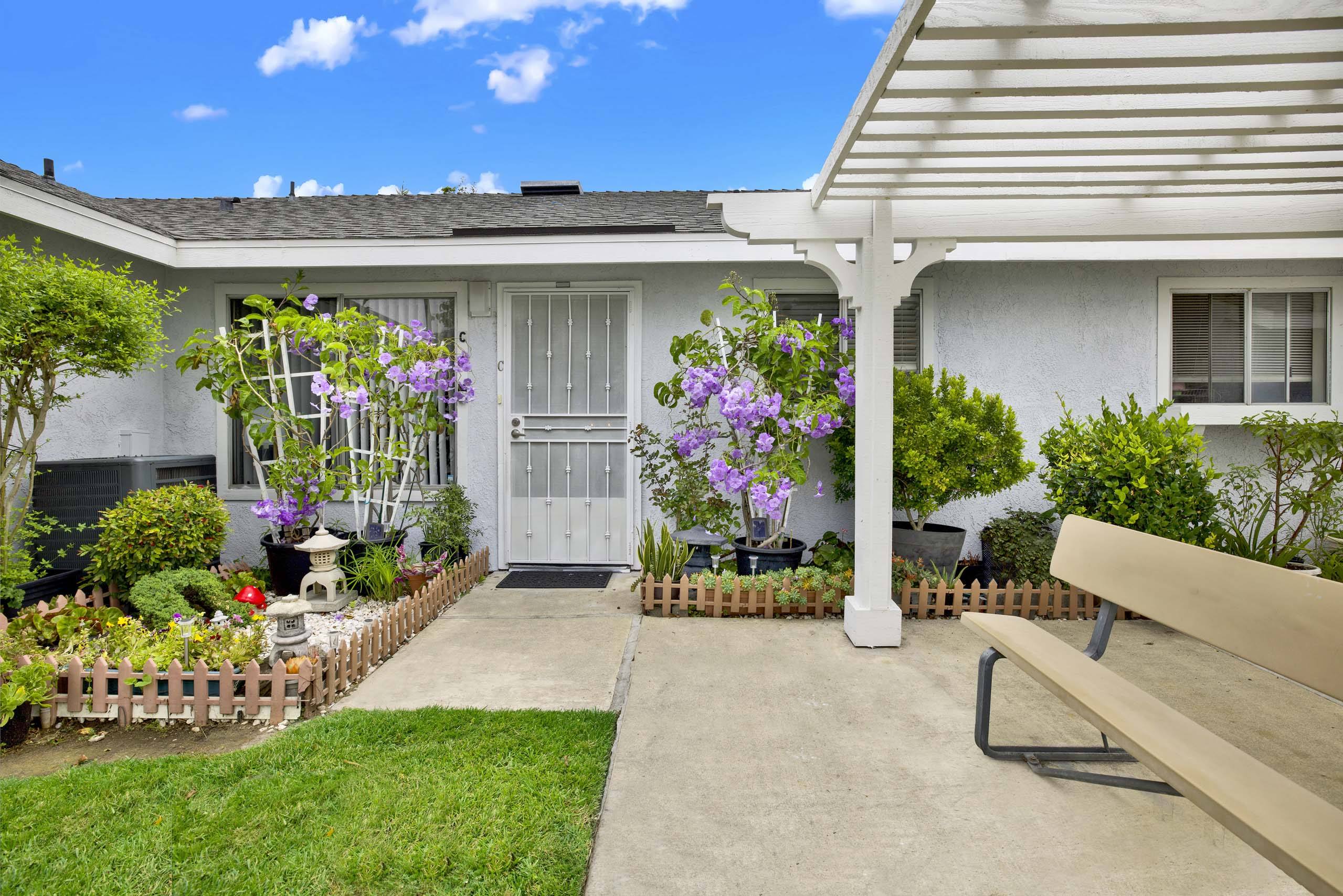 A white house with a porch and a bench in front.