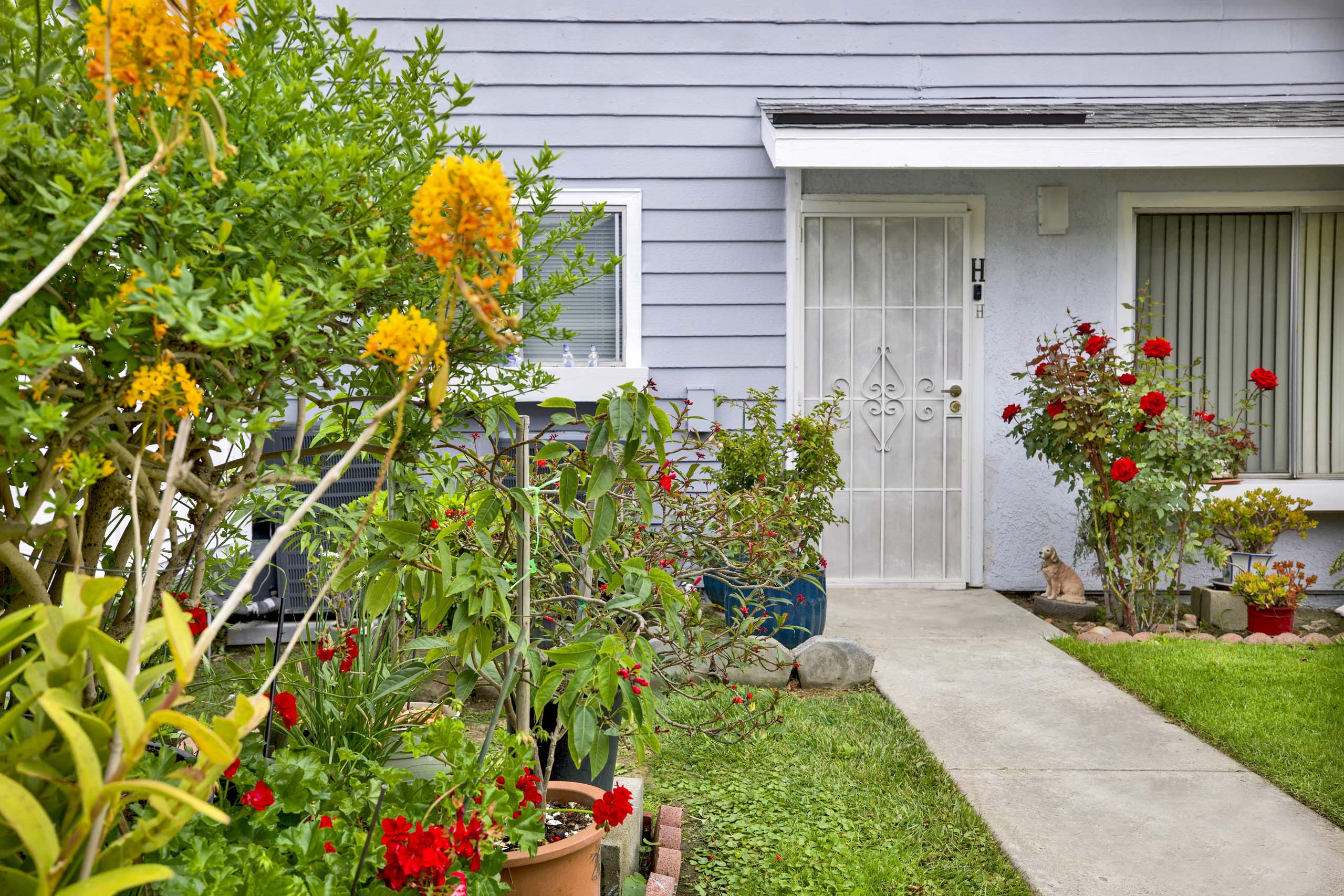A house with a white door and a white fence with a garden in front.