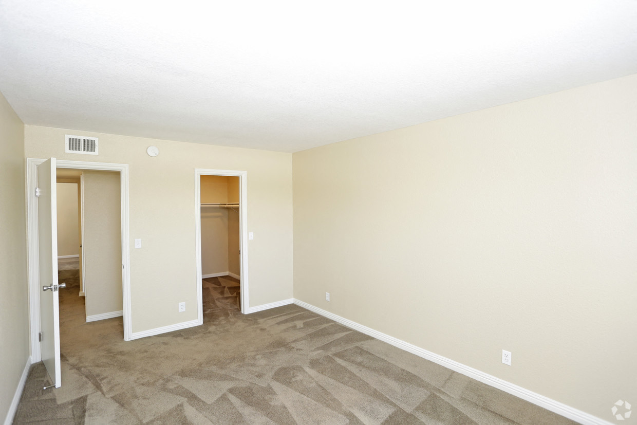 A room with a carpeted floor and a doorway leading to another room.