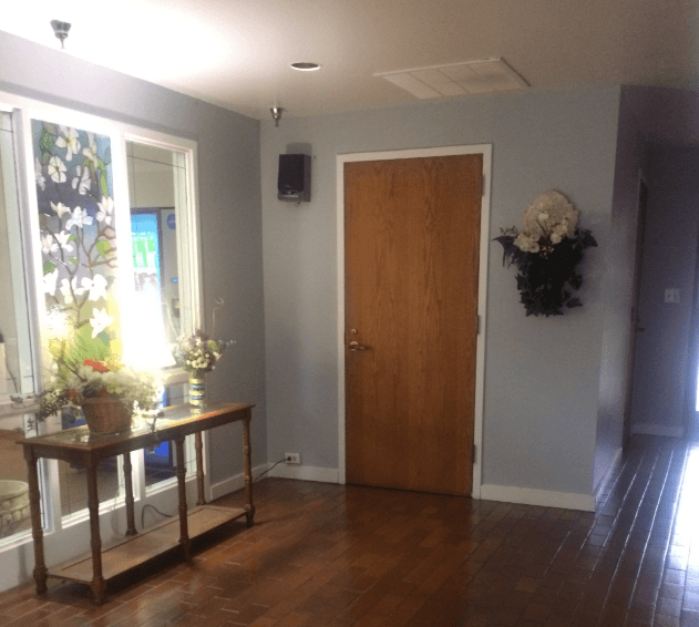 a room with a wooden door and a table with flowers on it