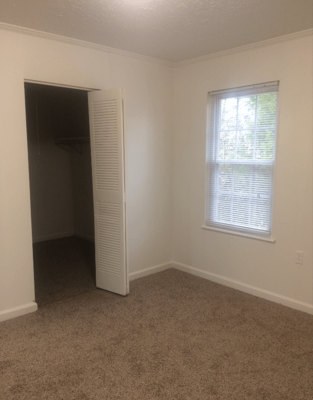 an empty room with a window and an open closet