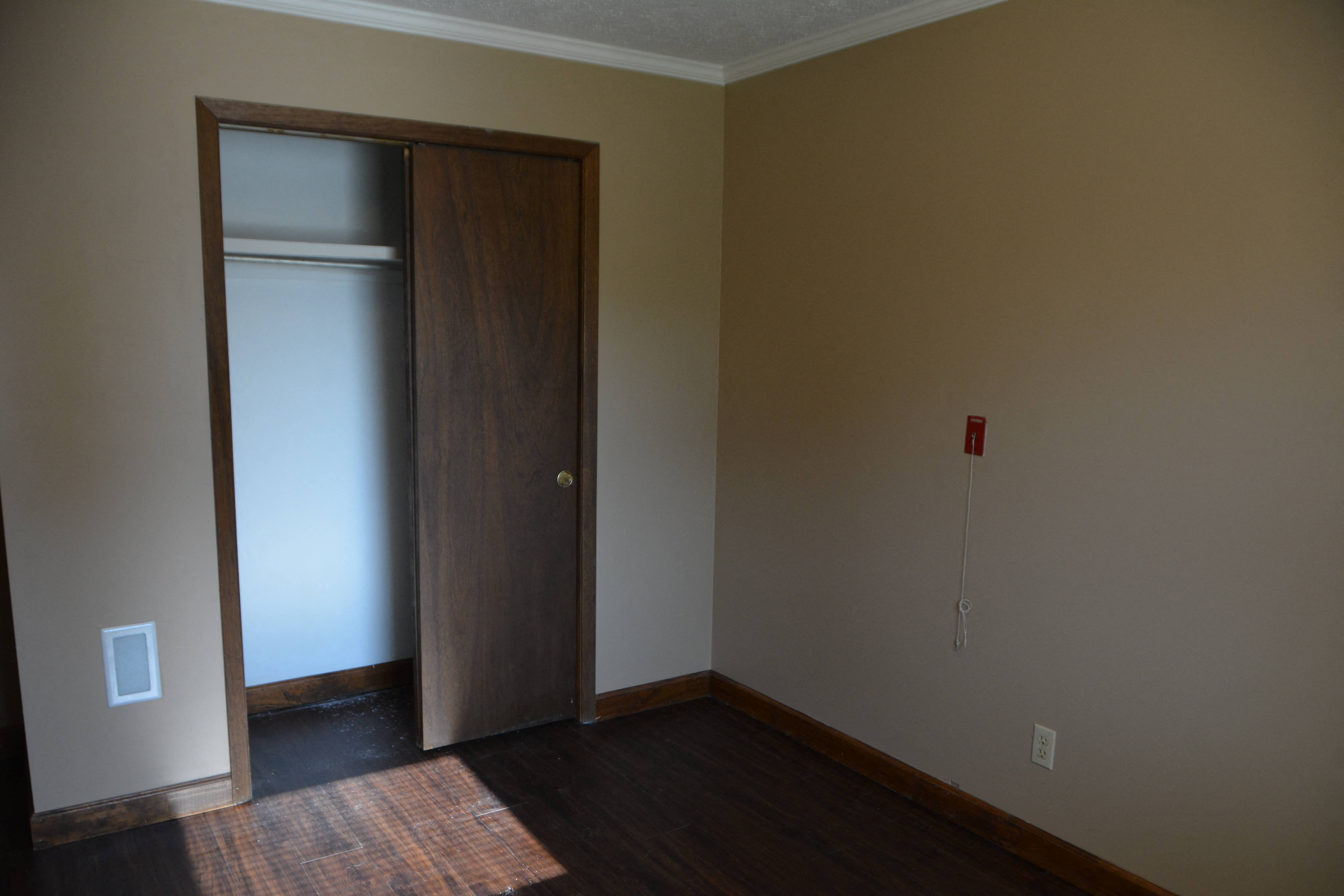 an empty living room with a door to a closet