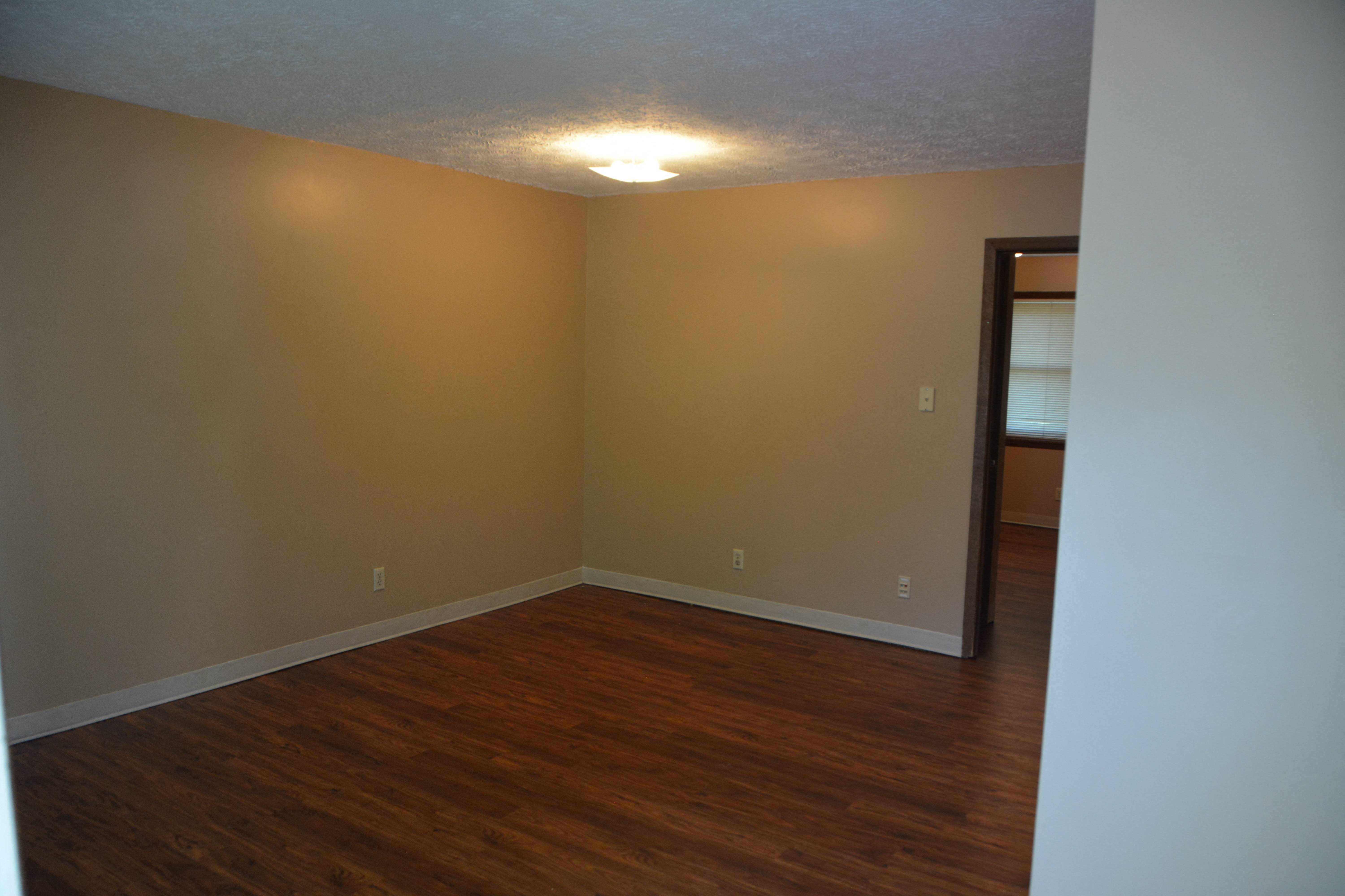 an empty living room with wooden floors and a ceiling light
