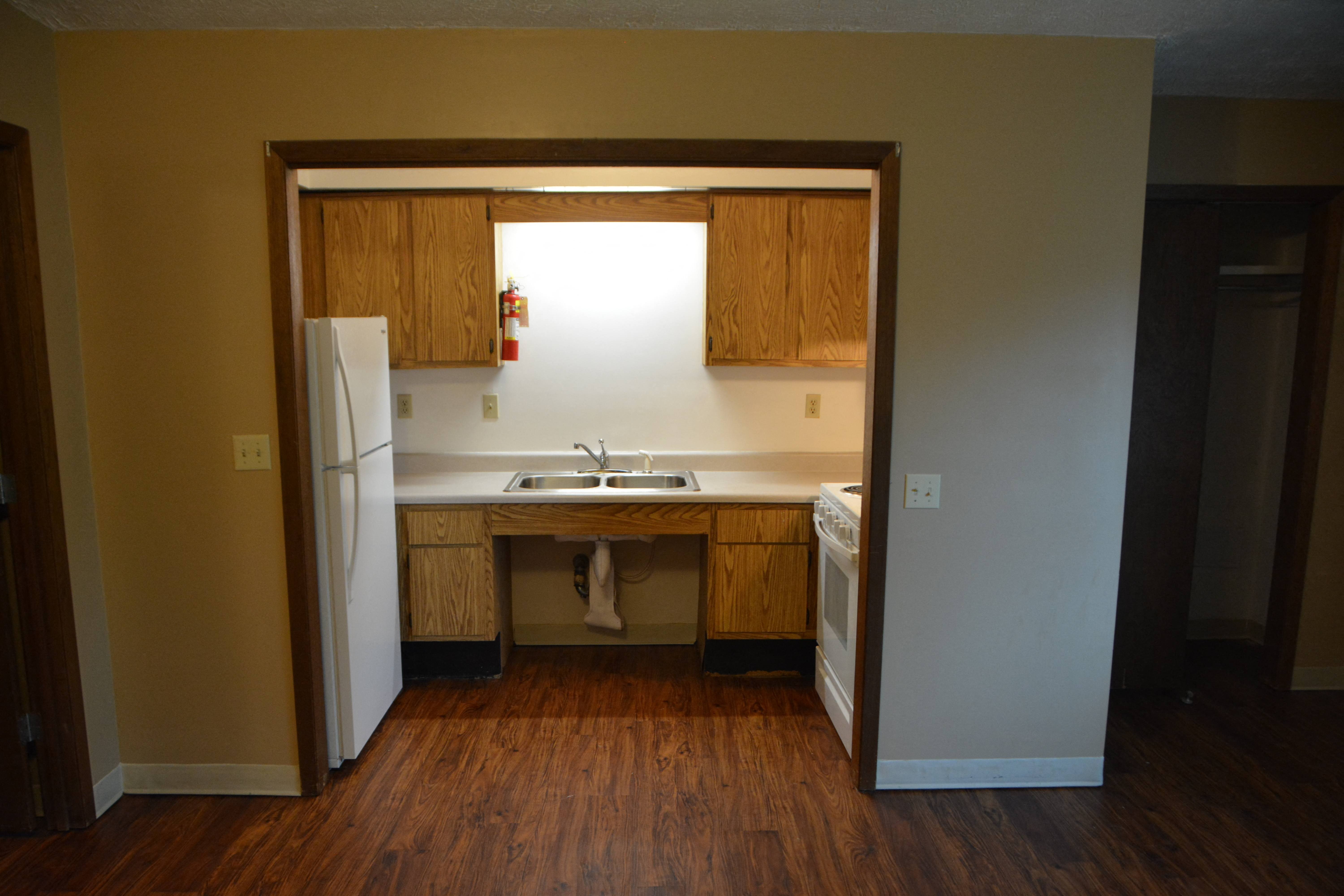 an empty kitchen with a sink and a refrigerator