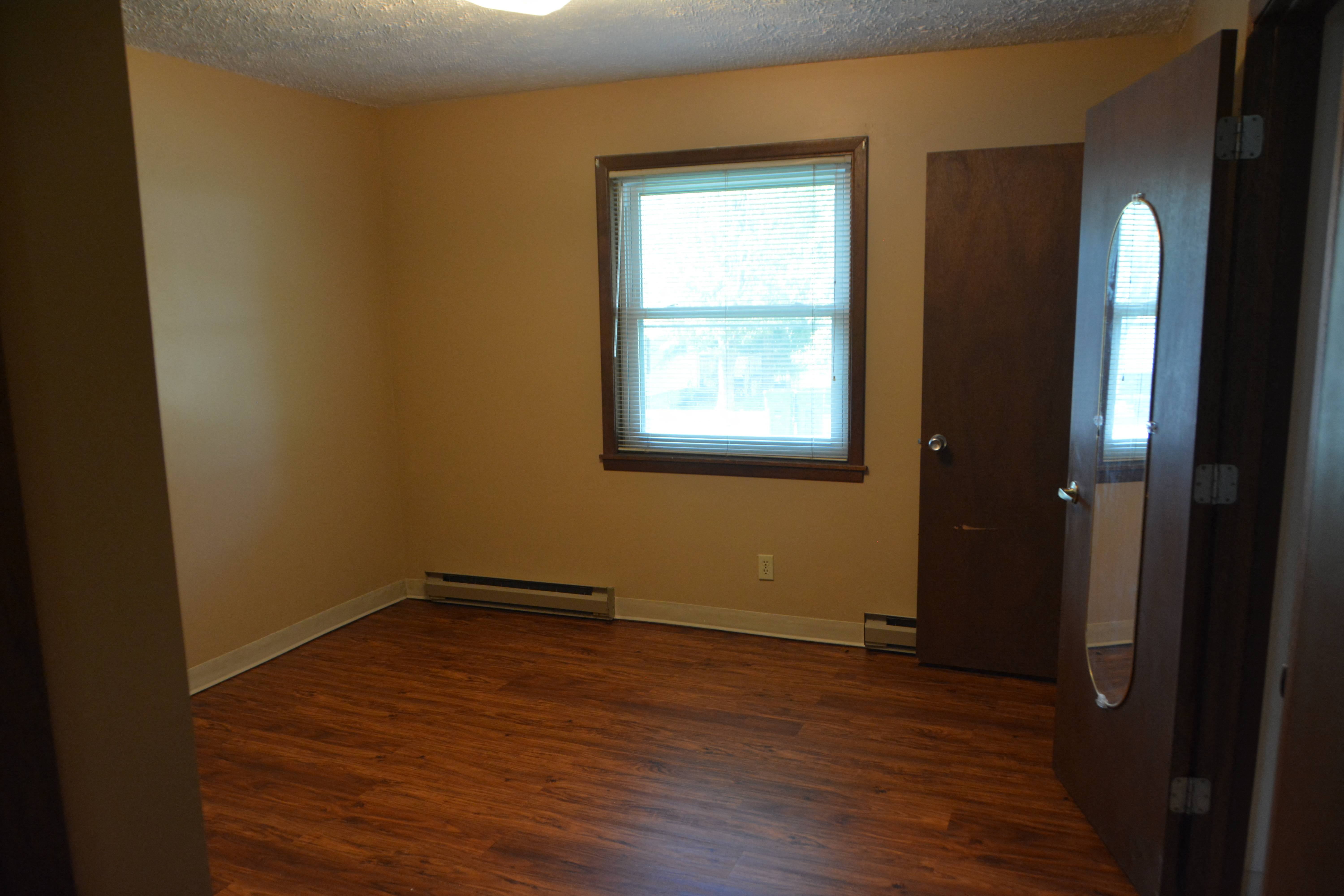 an empty living room with wood floors and a window