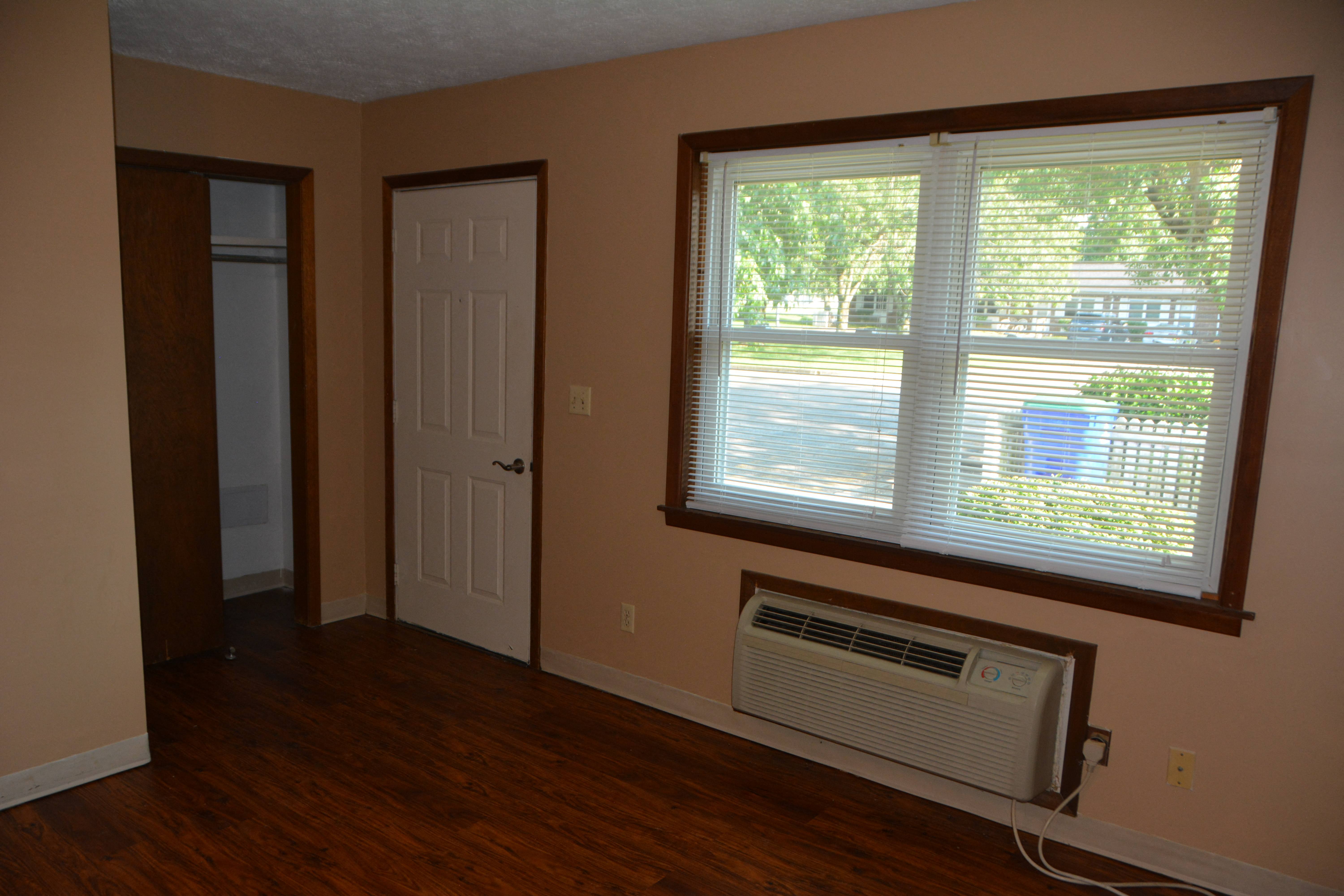 an empty living room with a window and a air conditioner