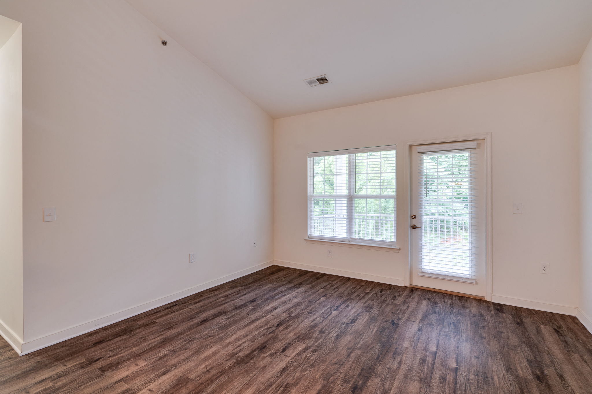 a living room with wood floors and white walls and a door and window