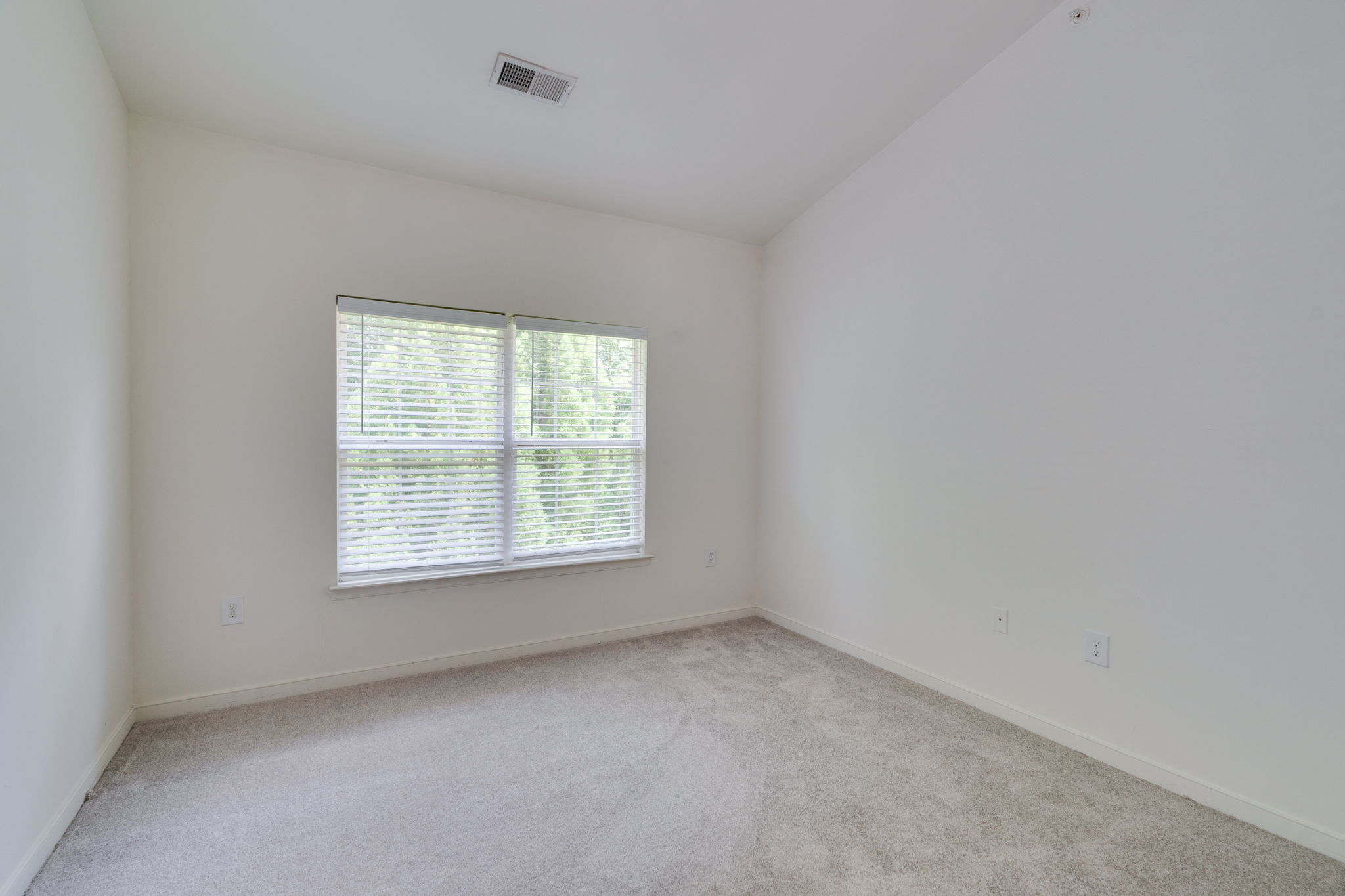 an empty bedroom with a window and carpeting