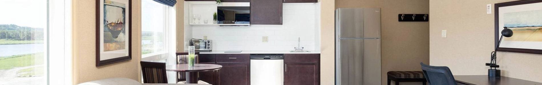 A kitchen with a refrigerator, table and chairs.