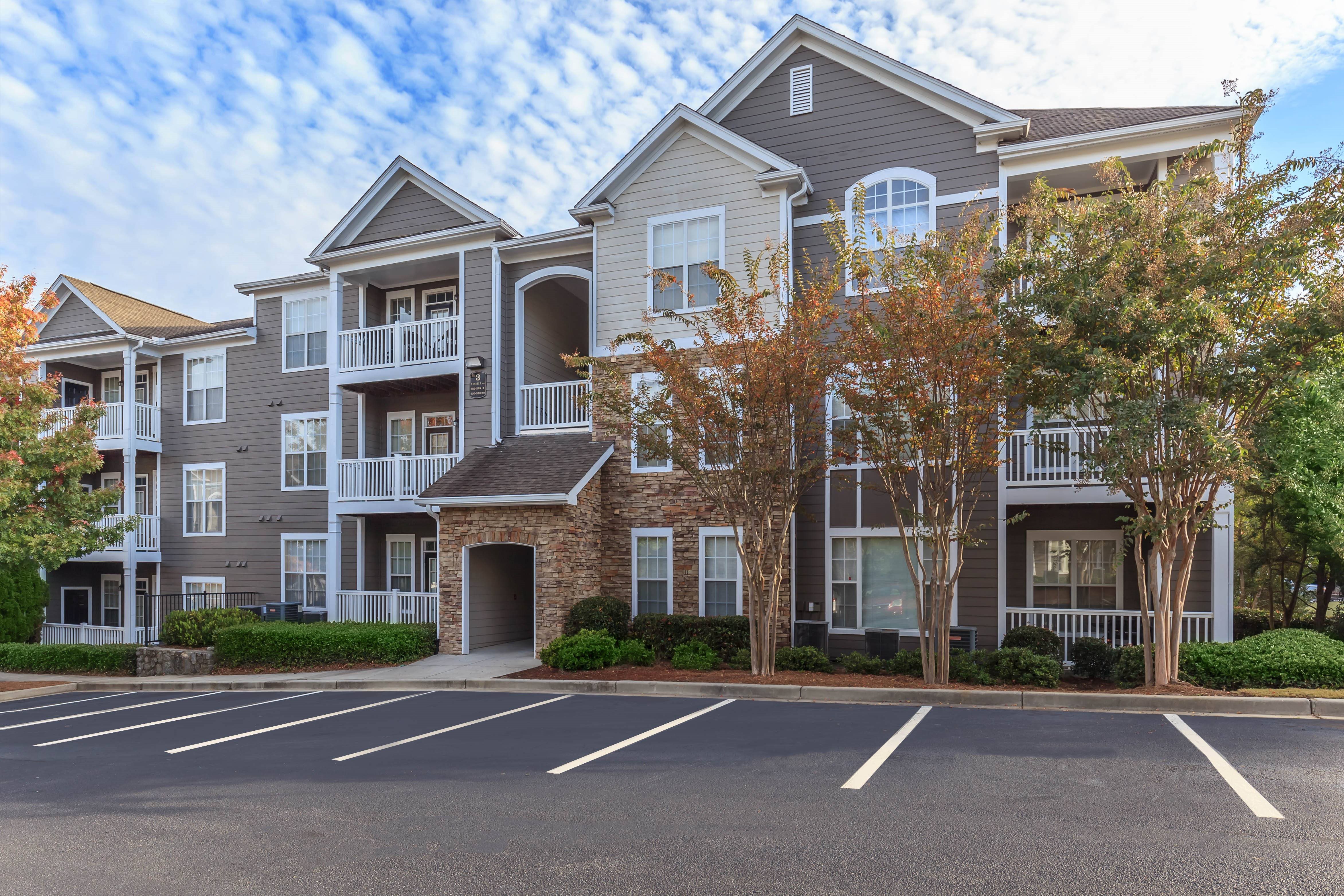 an apartment building with a parking lot and trees