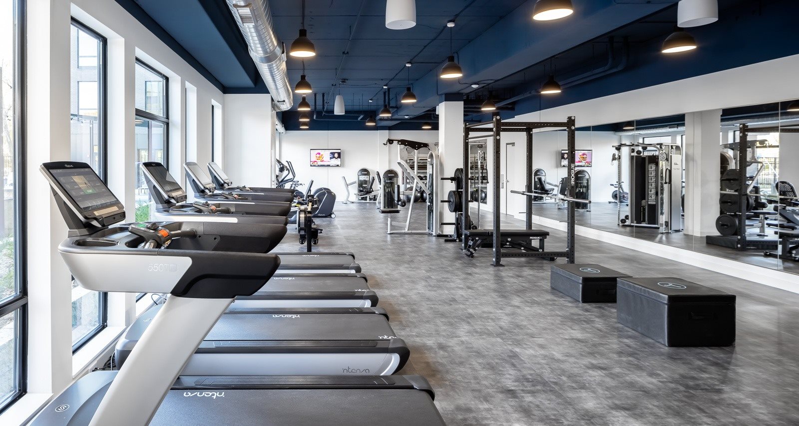 Treadmills and mirror in forefront of gym for apartment residents