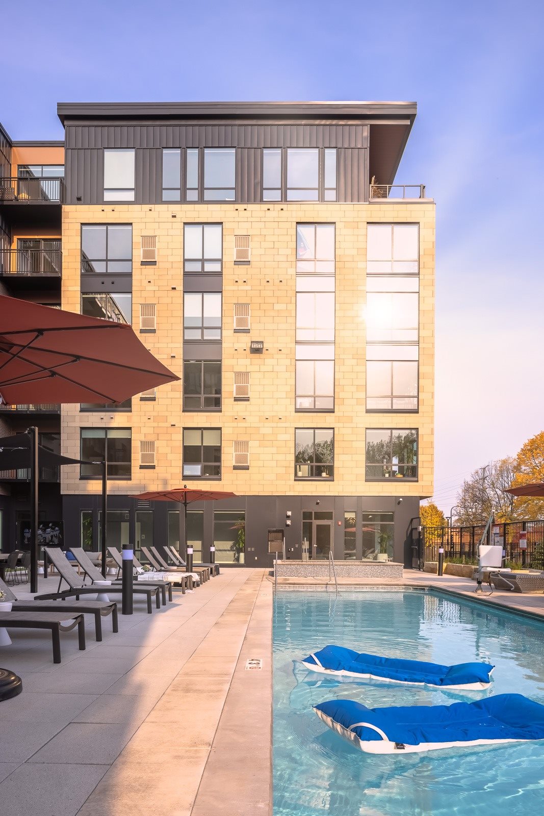 Outdoor heated pool on terrace with sunshine reflecting off windows