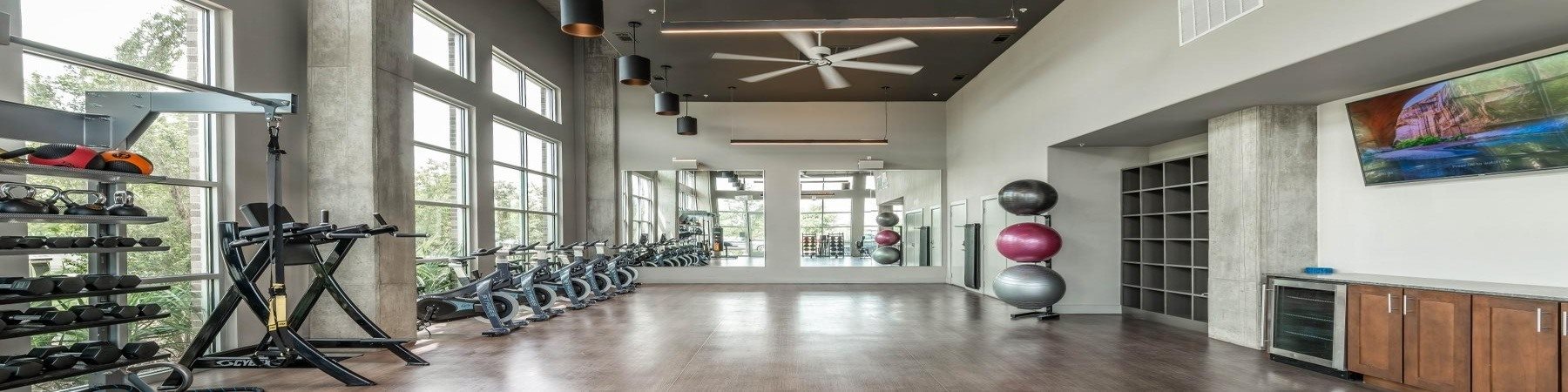 A gym with a row of exercise bikes and a row of dumbbells.