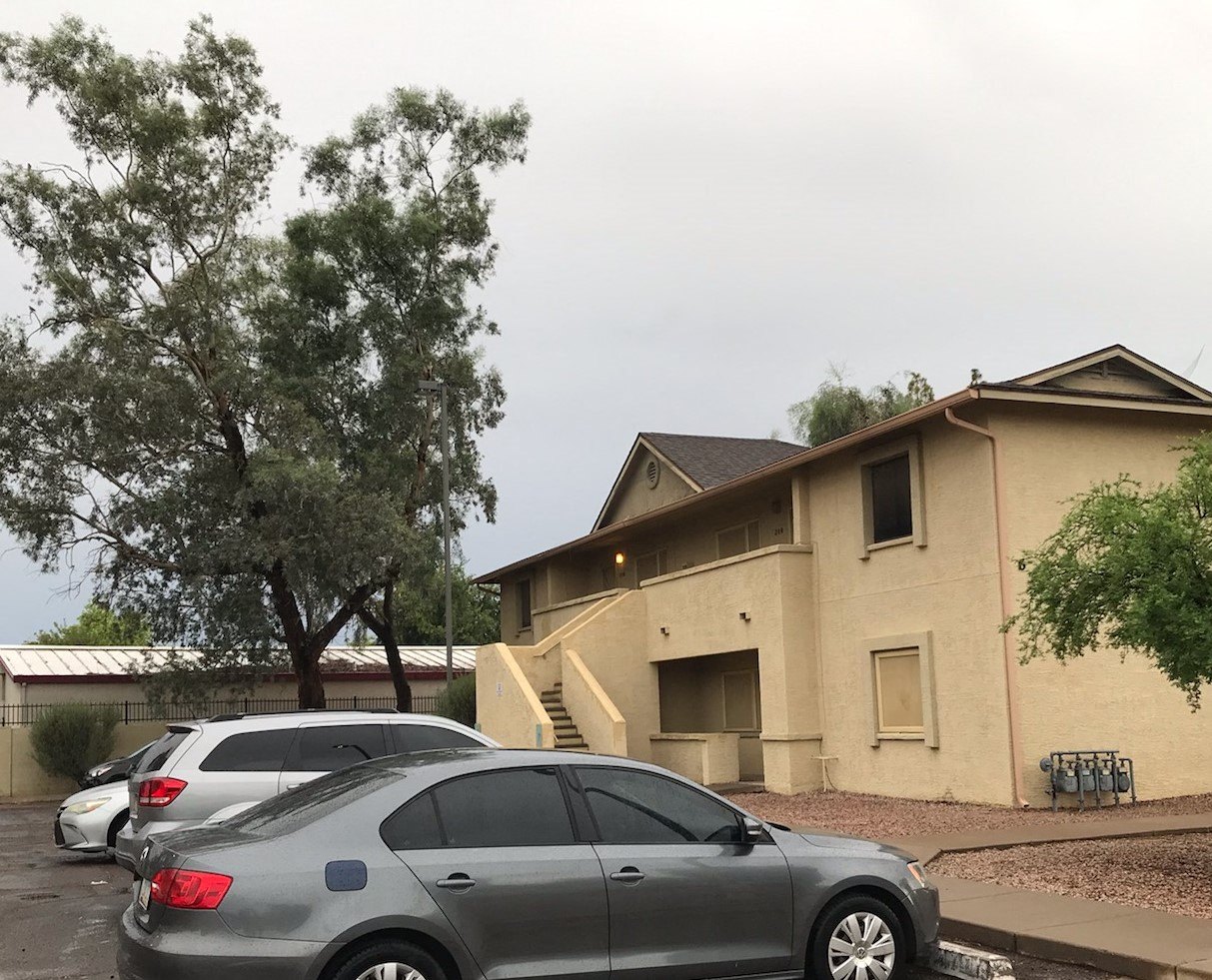 a tan building with cars parked in front of it