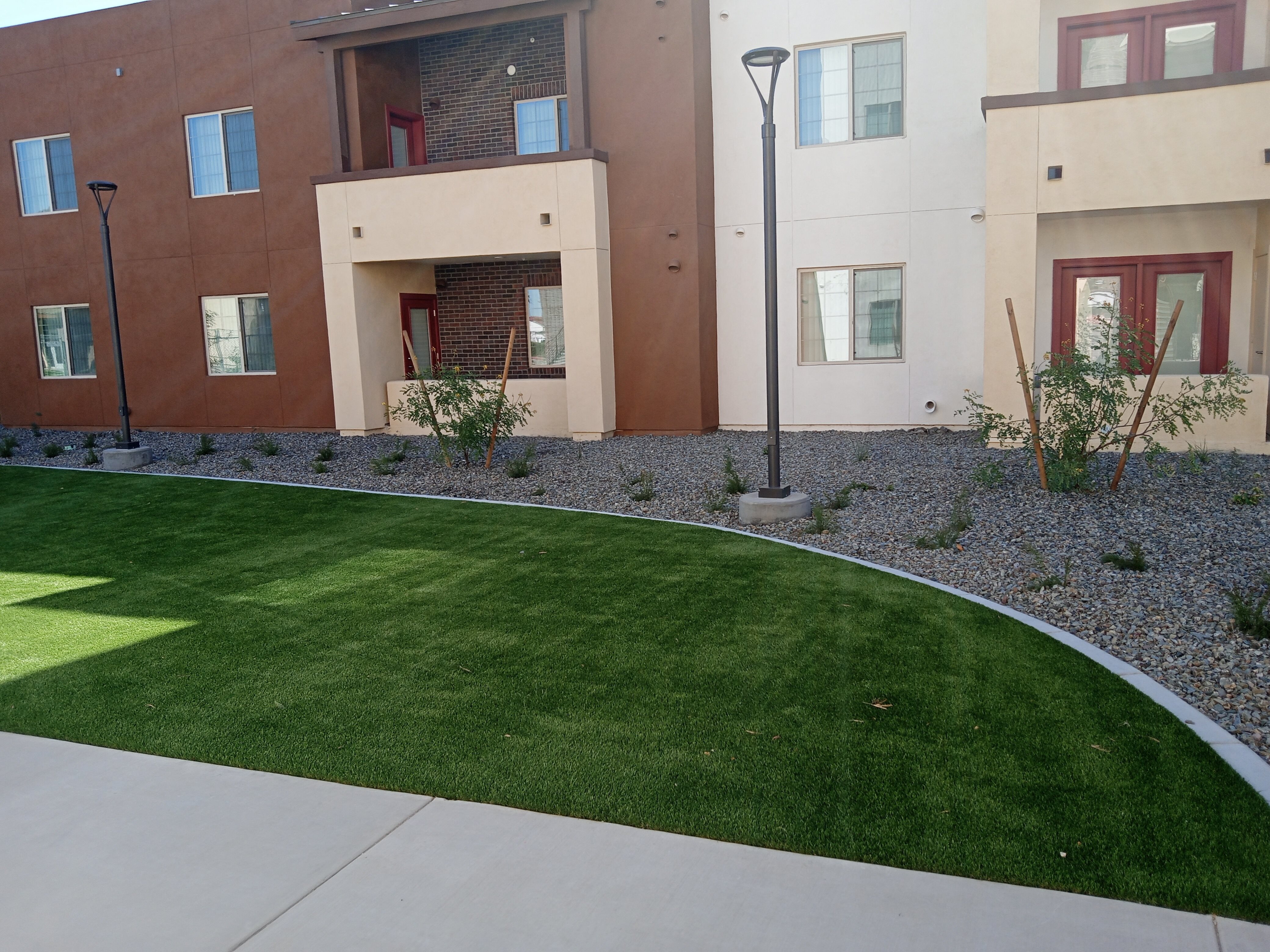 the front yard of an apartment building with green grass and a sidewalk