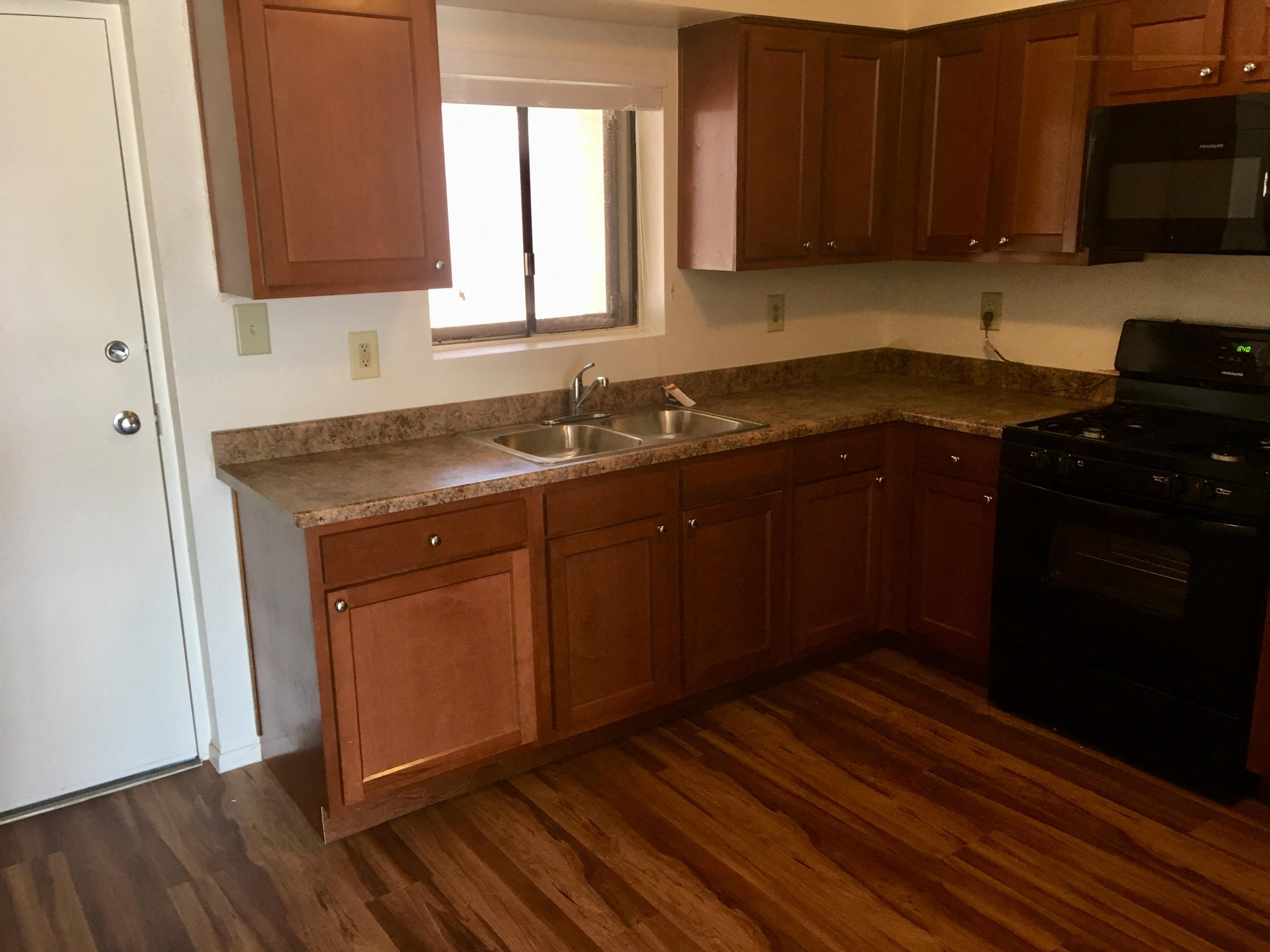 an empty kitchen with wooden floors and wooden cabinets