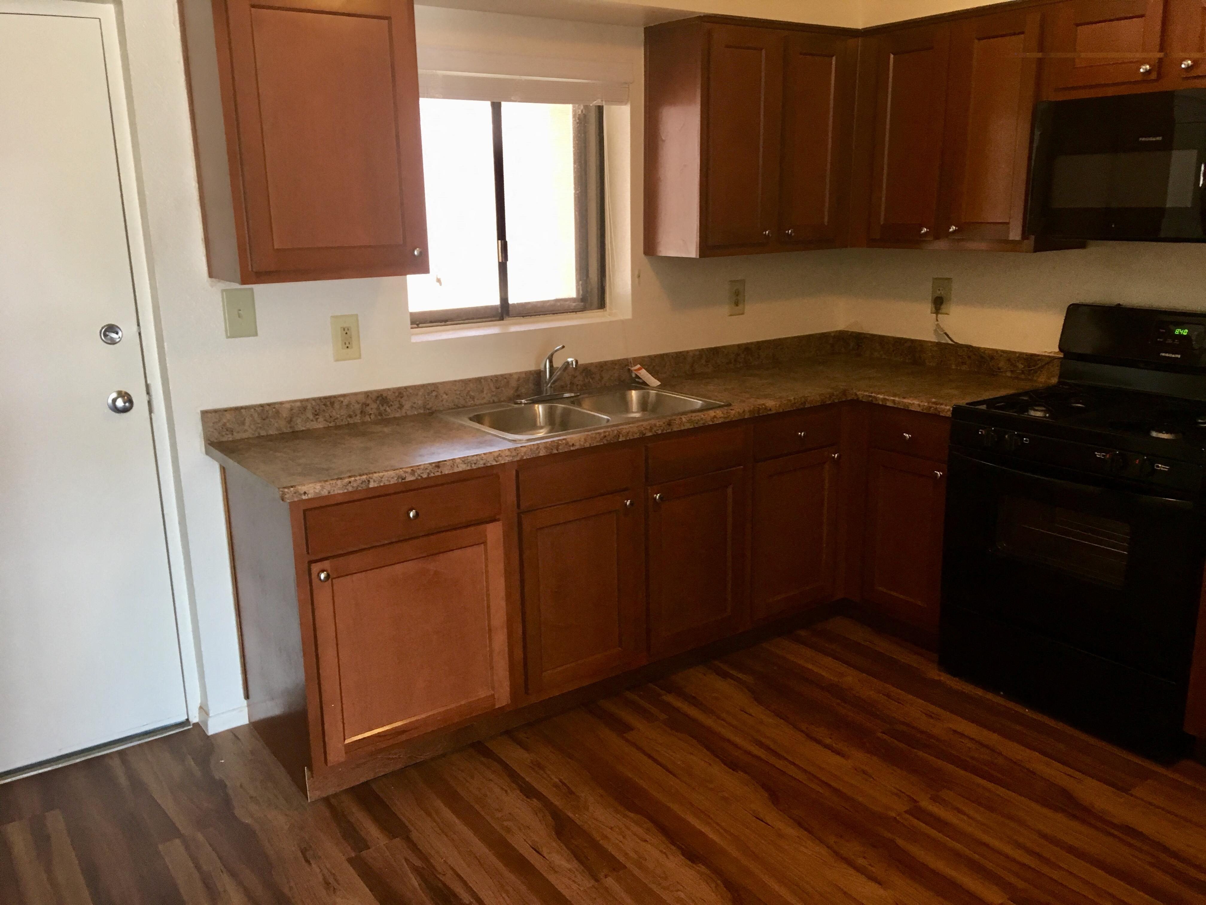 an empty kitchen with wooden floors and wooden cabinets