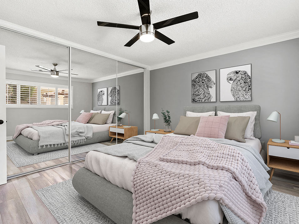 Carpeted bedroom with ceiling fan and large mirrored closet.