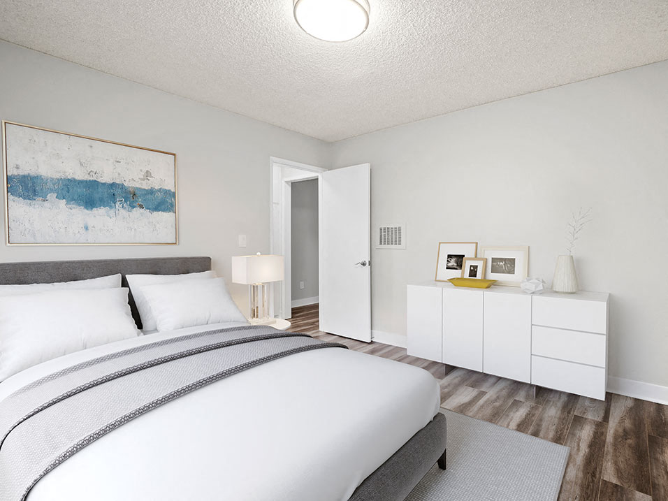 Hardwood floored bedroom with private closets and ceiling-mounted light fixtures..