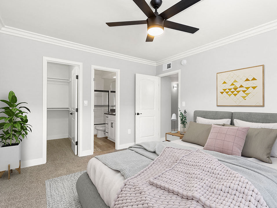 Carpeted bedroom with ceiling fan and private bathroom.