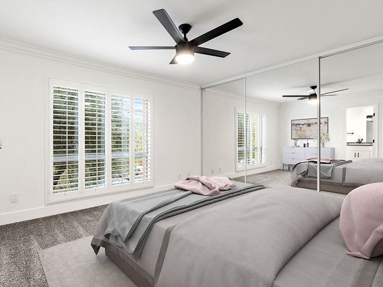 Carpeted bedroom with ceiling fan and large natural light window..