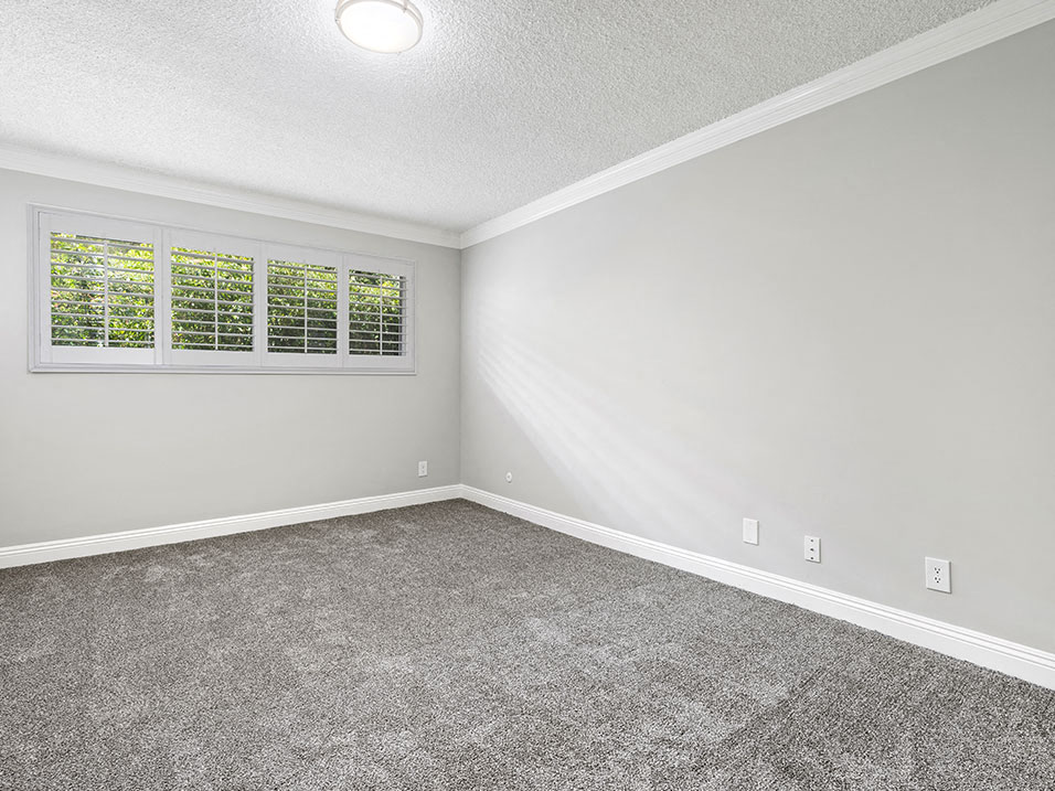 Carpeted bedroom with crown moulding and large exterior windows.