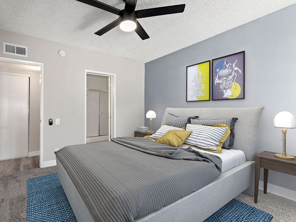 Carpeted bedroom with ceiling fan and private bathroom.