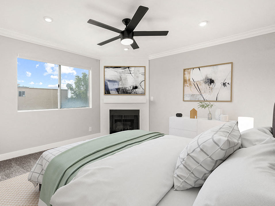 Carpeted bedroom with ceiling fan and private fireplace.