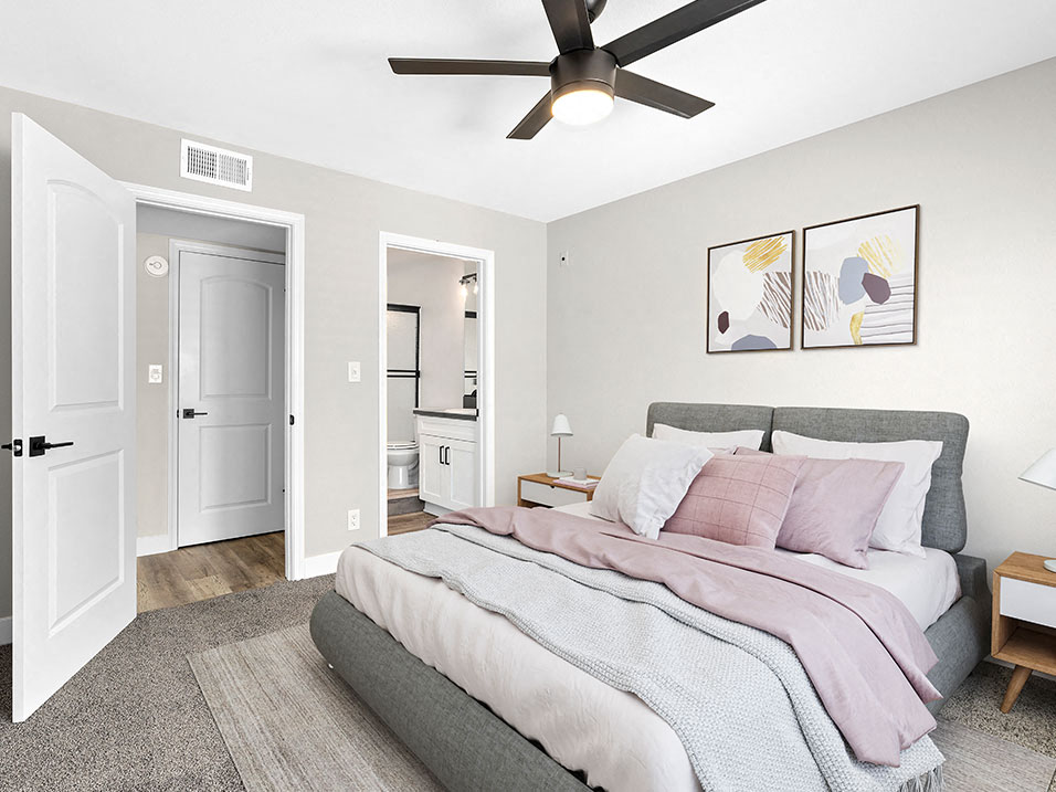 Carpeted bedroom with ceiling fan and private bathroom.