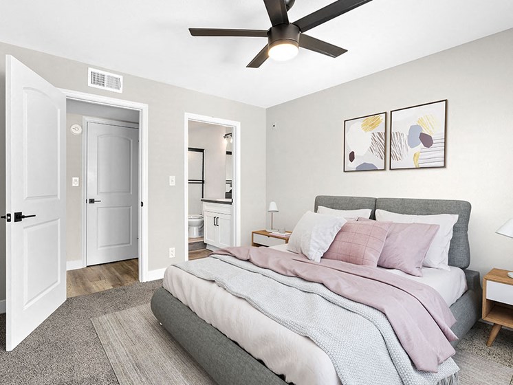 Carpeted bedroom with ceiling fan and private bathroom.