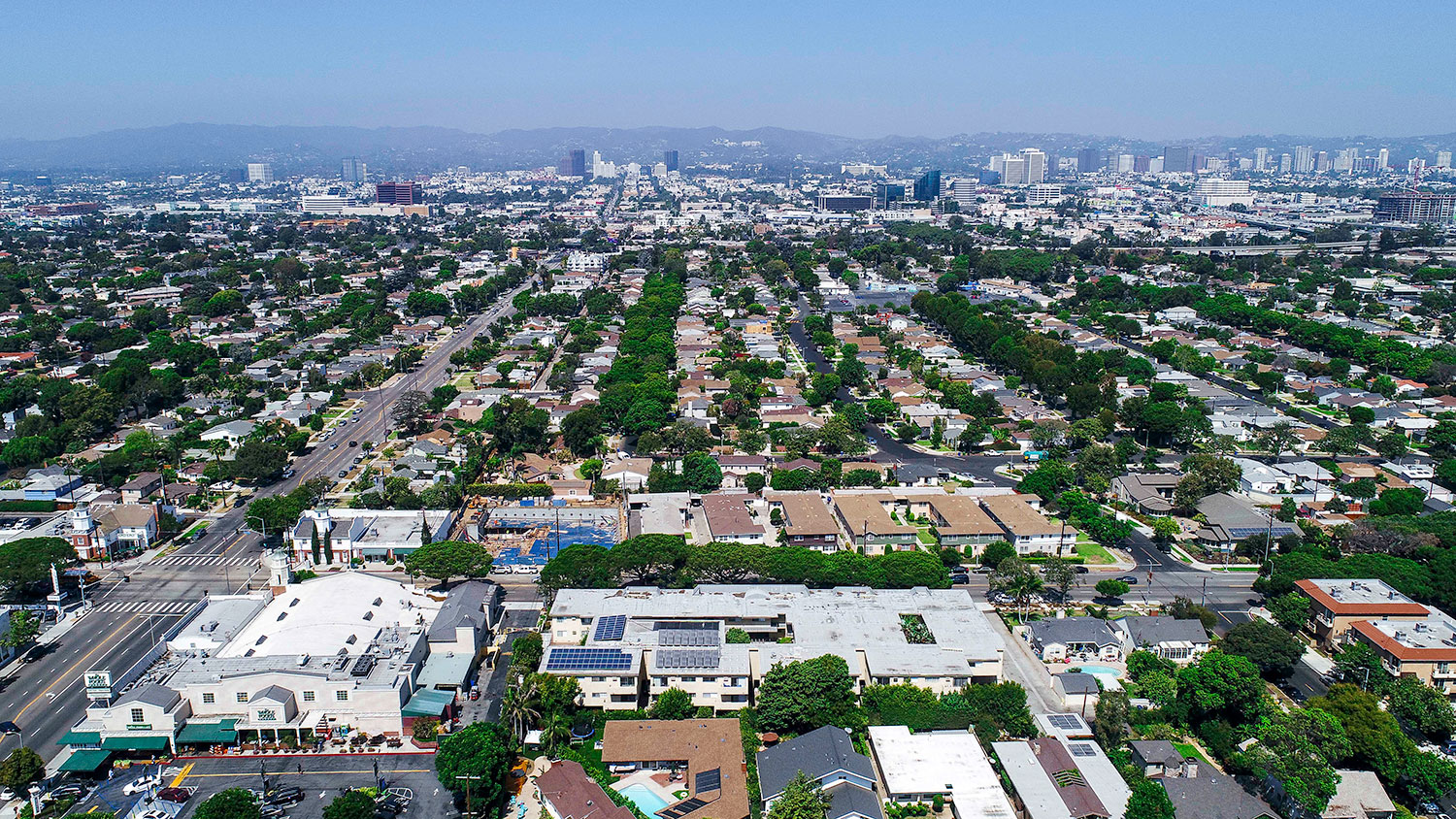 Aerial drone view of National Apartments depicting roof-mounted solar panels and adjacency to Whole Foods Market.