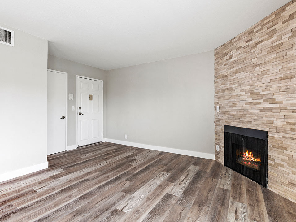 Hardwood floored living room with stone accented fireplace.